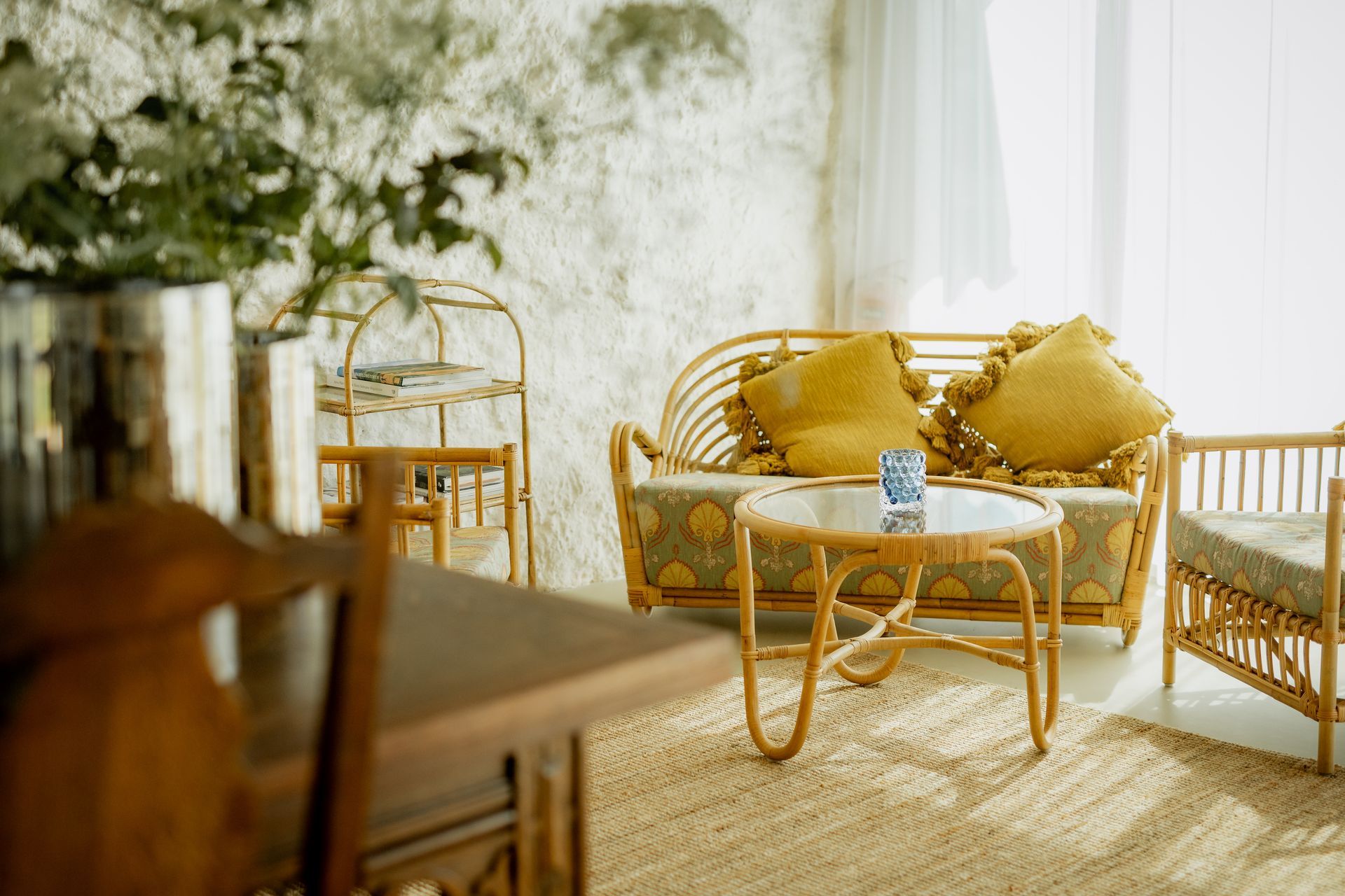 Wicker furniture in a sunlit room with yellow pillows and a round coffee table.