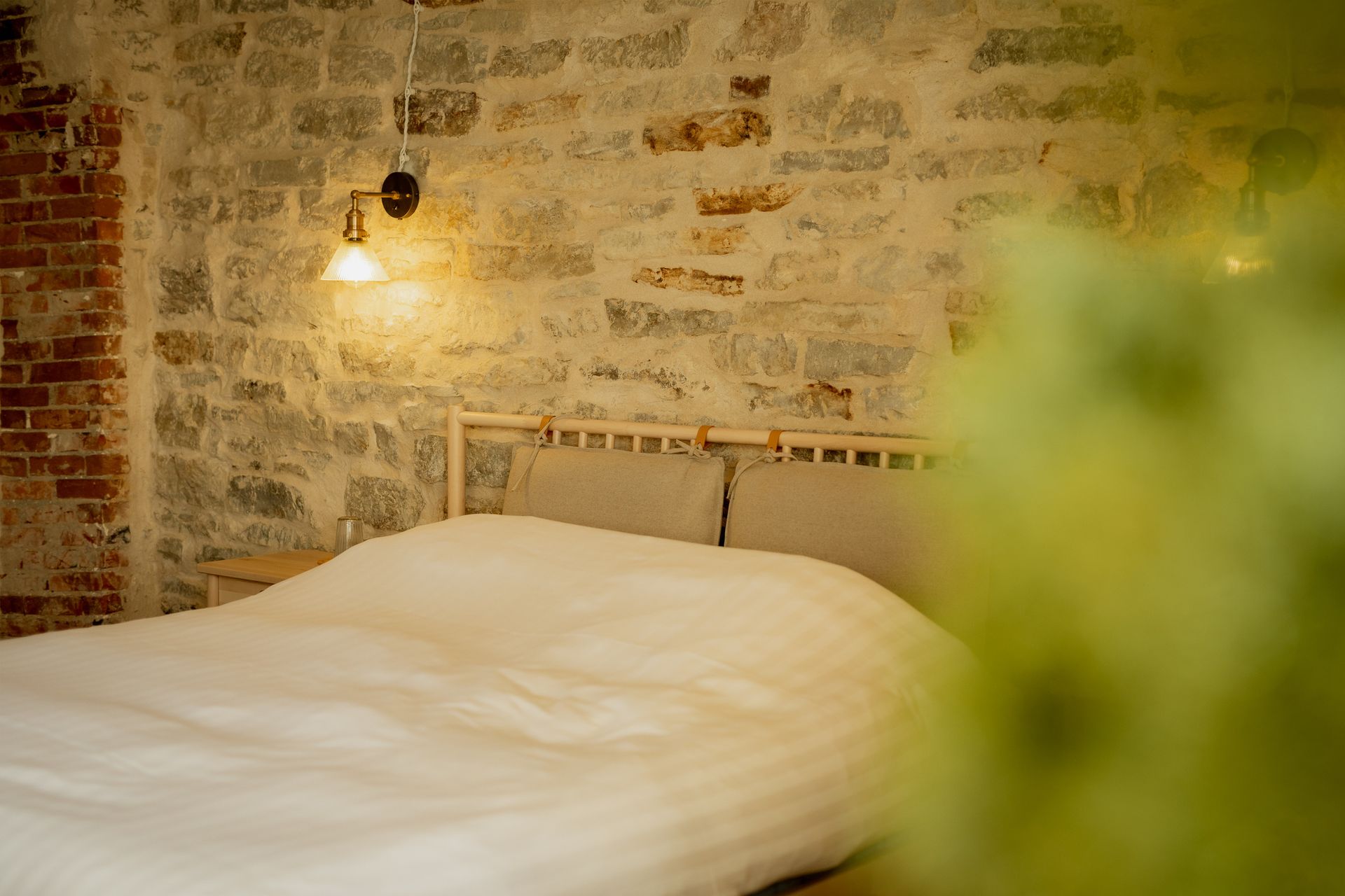 Bedroom with bed, stone wall, and hanging light fixture.