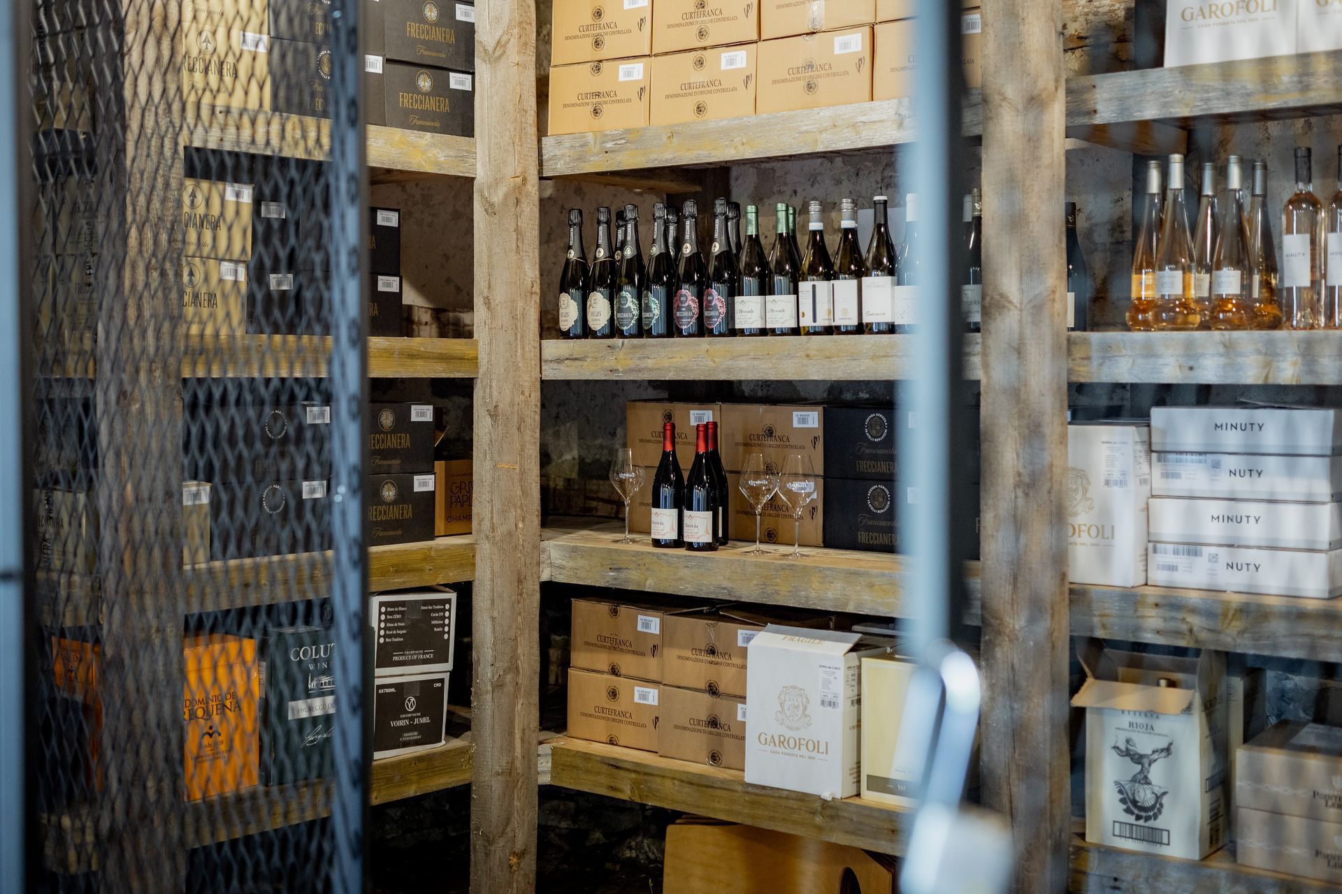 Shelves stocked with wine bottles and boxes in a rustic cellar.
