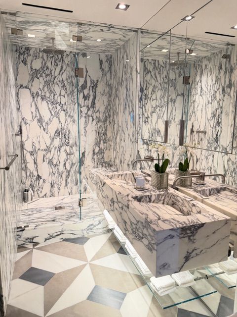 Marble-tiled bathroom with glass shower, vanity, and geometric floor