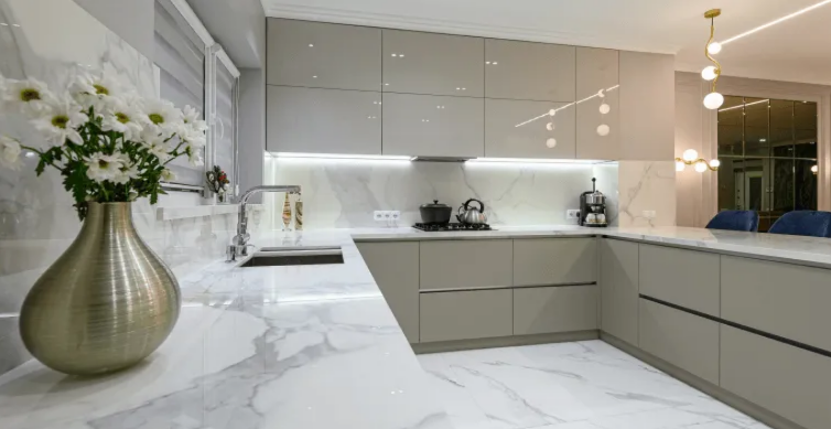 Modern white kitchen with marble countertops, beige cabinets, and a vase of flowers in the foreground