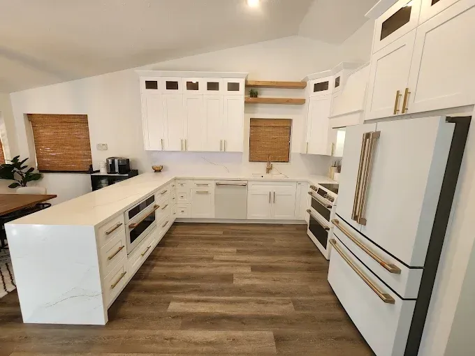 Bright modern white kitchen with island, wood floors, and stainless steel appliances