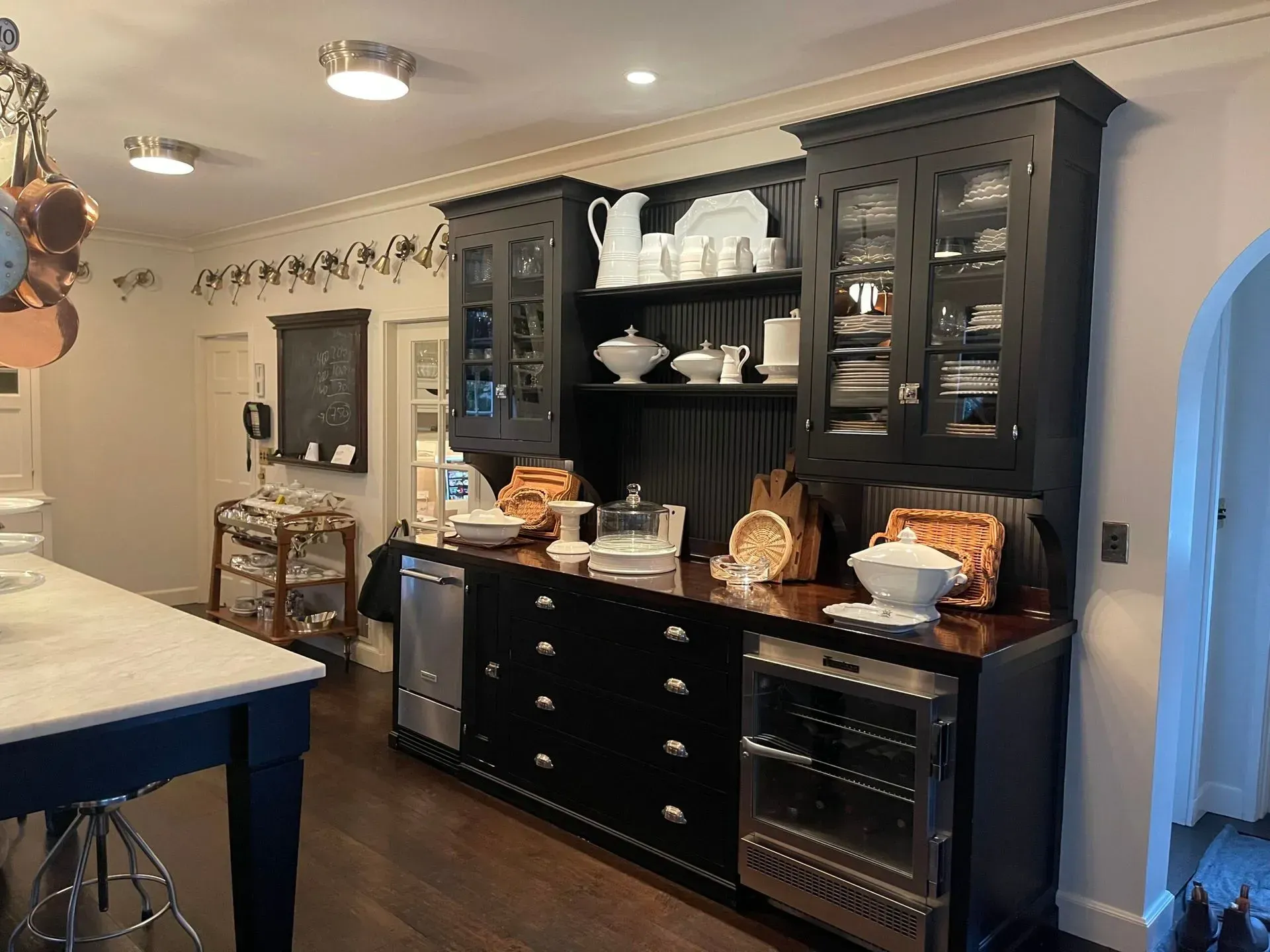 Kitchen with dark cabinets, white countertops, and a central island in a warmly lit home interior.