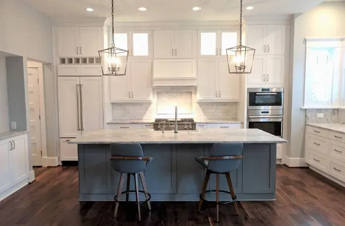 Bright white kitchen with large island, pendant lights, and dark wood floors