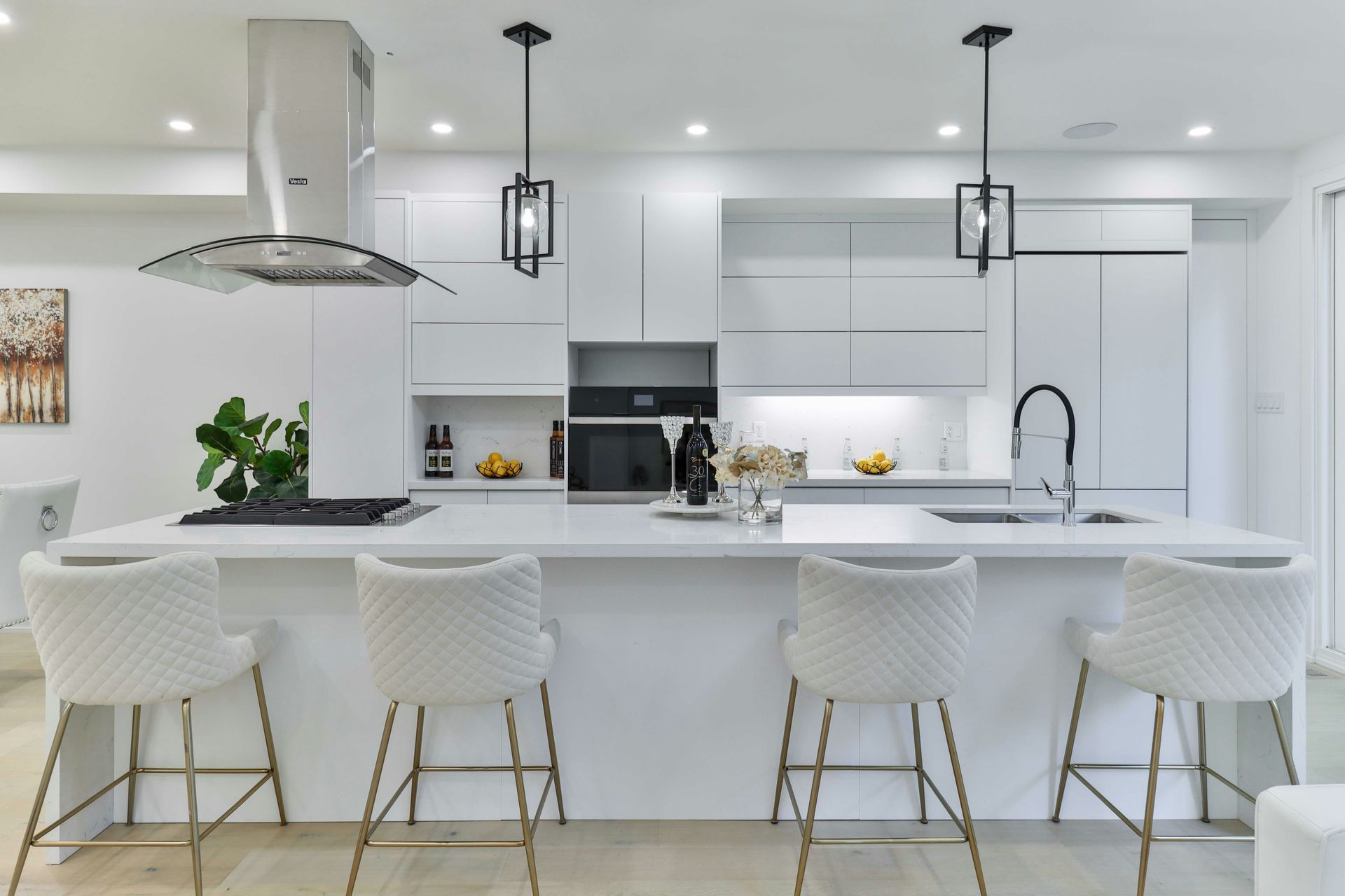 Bright white modern kitchen with island, pendant lights, and four stools, styled in minimalist decor