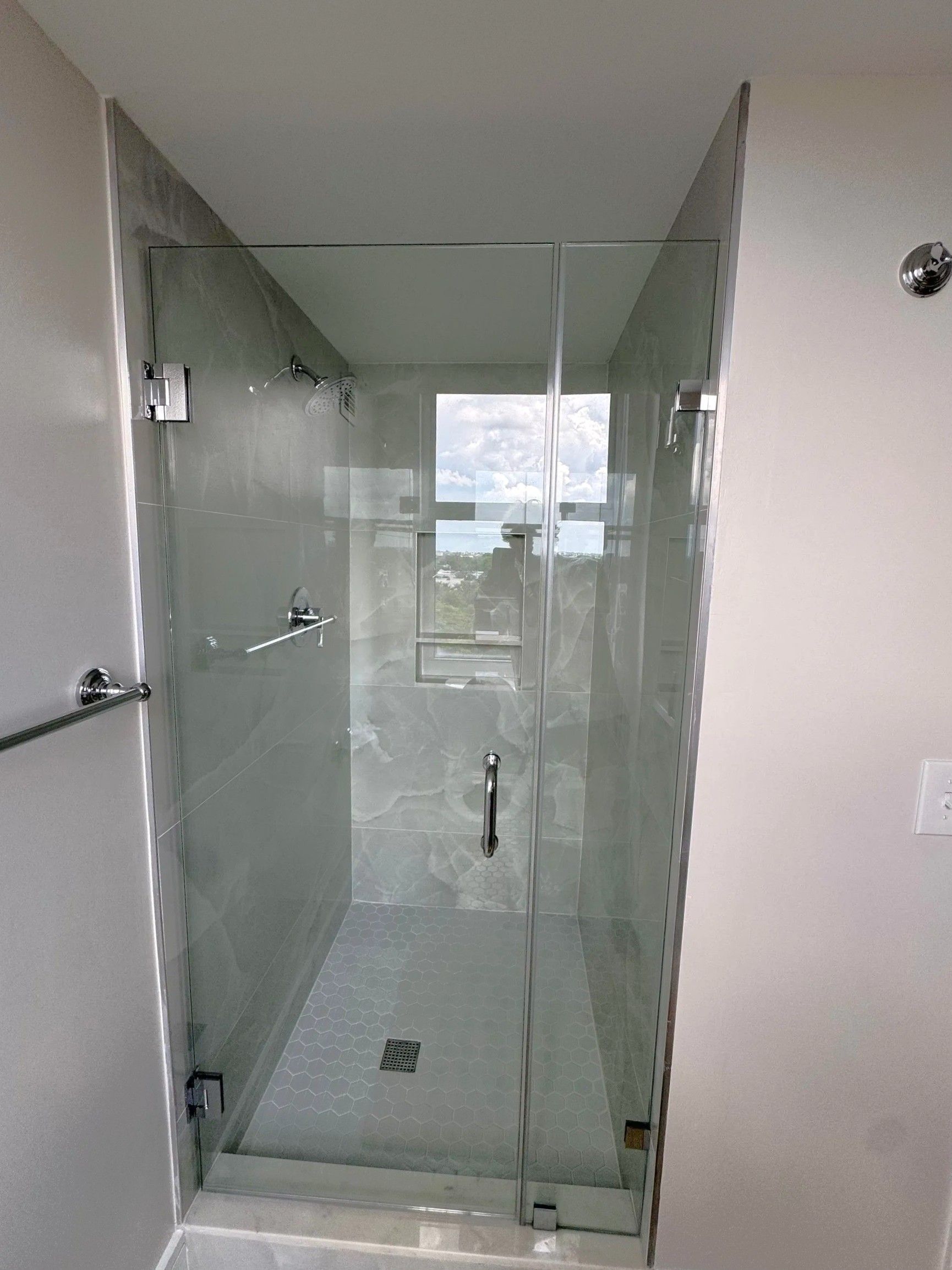 Modern glass shower stall with clear doors and white tile walls