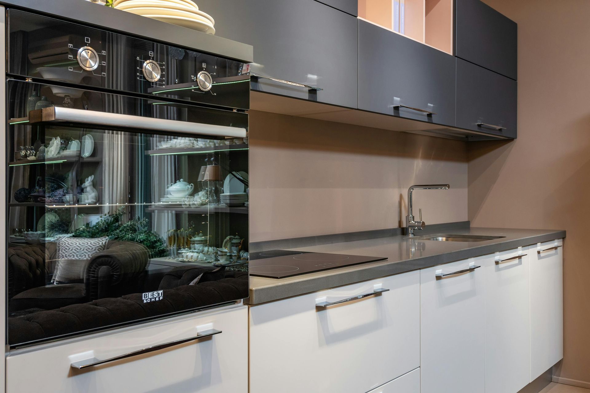 Modern kitchen with black oven, white cabinets, and a gray countertop with sink.