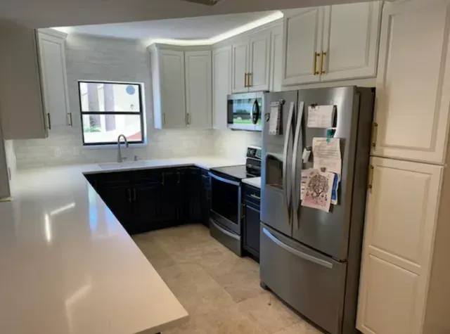 Modern kitchen with white cabinets, black island, stainless steel appliances, and a window over the sink