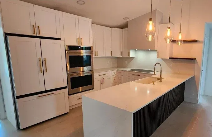 Modern white kitchen with island, pendant lights, built-in oven, and stainless steel sink