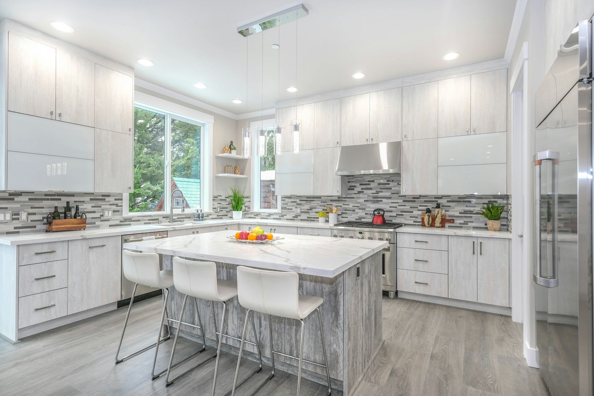 Bright white modern kitchen with island, bar stools, and large windows