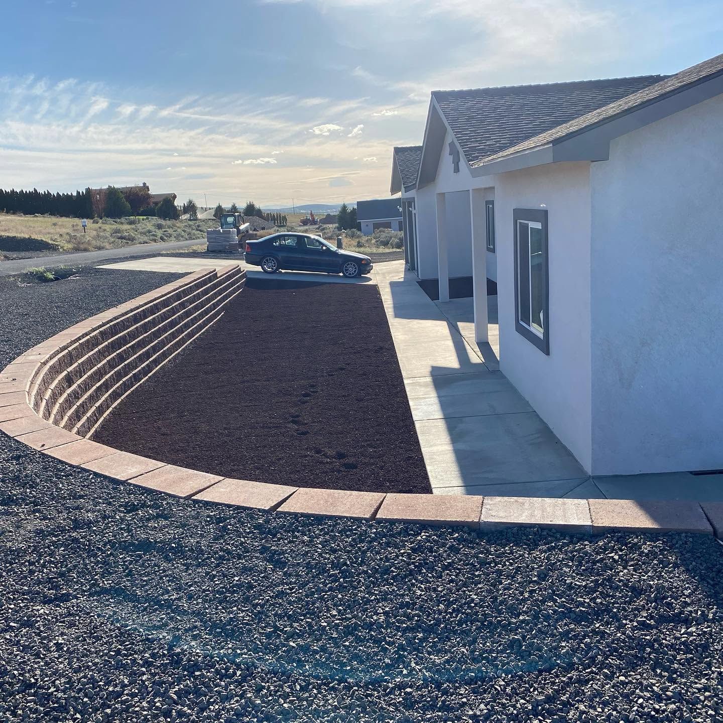 White house with tiled roof beside a curved gravel driveway in a sunny rural setting
