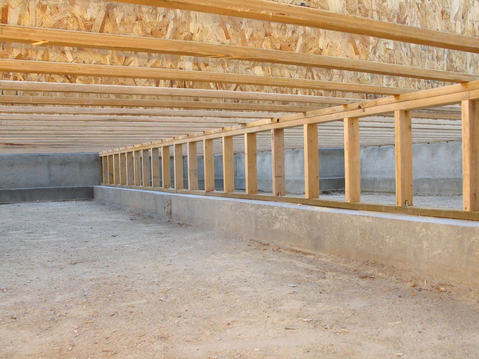 Wooden floor joists over a concrete foundation in an unfinished basement construction site