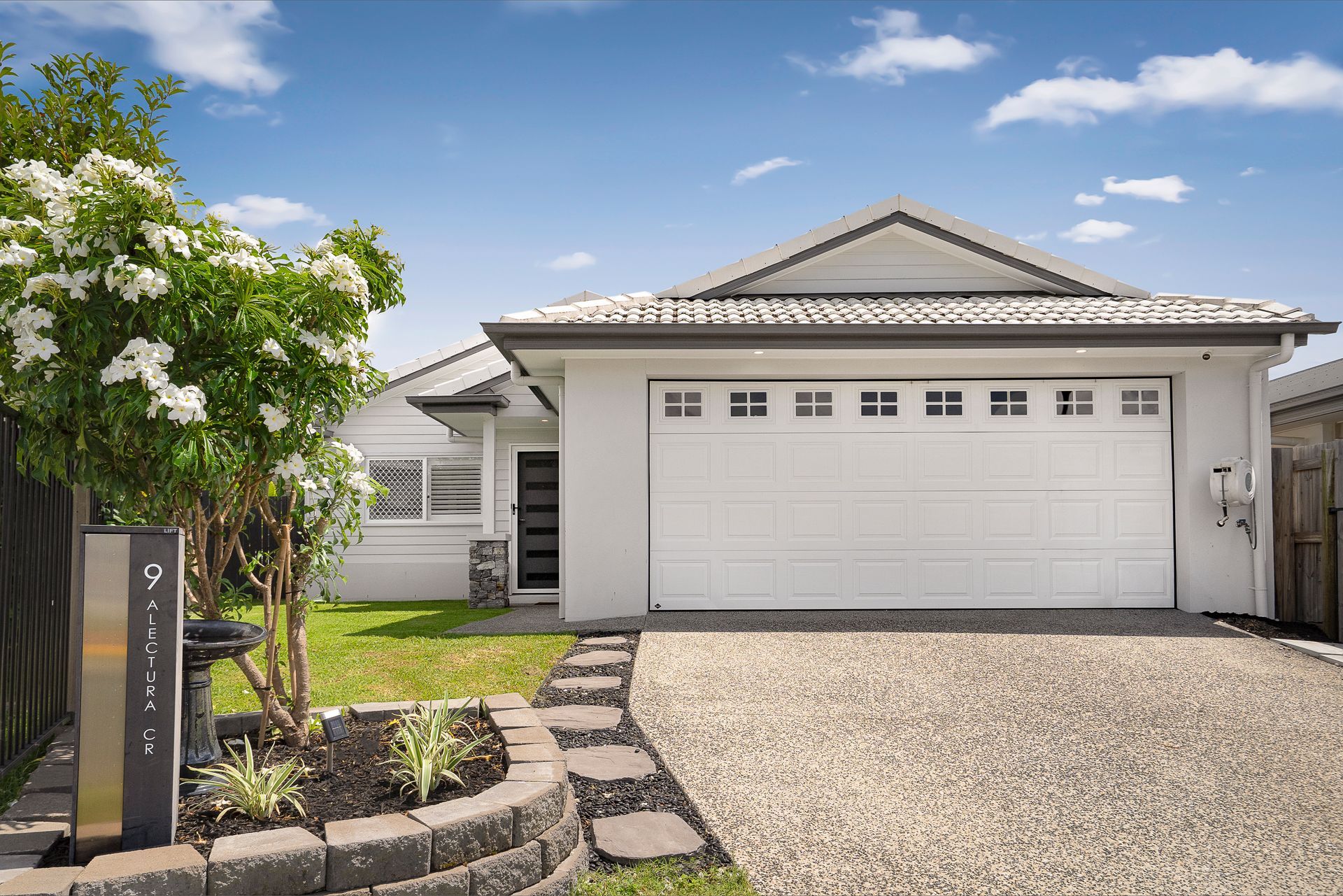 A white house with a wooden door and a concrete driveway.