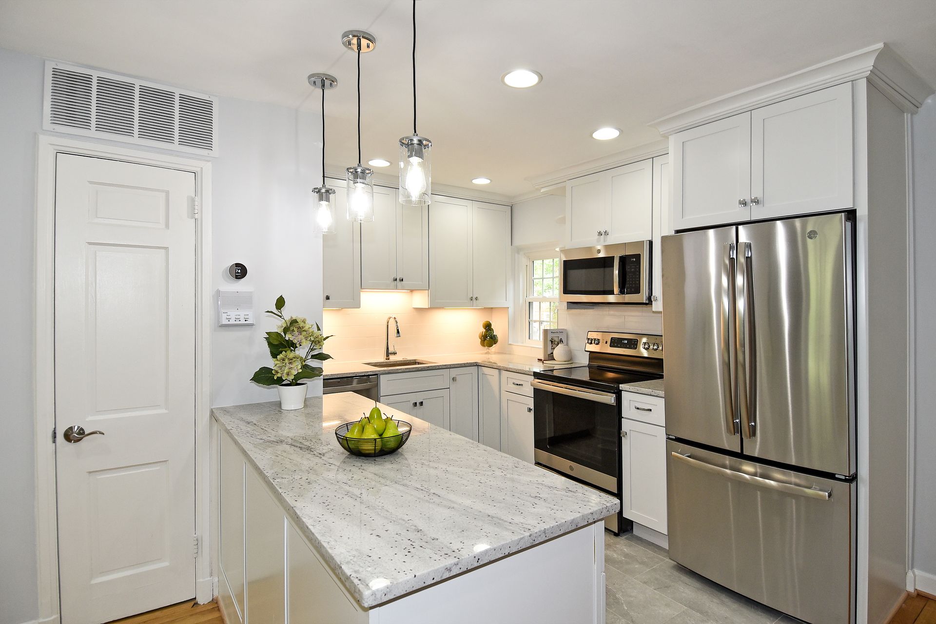 A kitchen with white cabinets and stainless steel appliances
