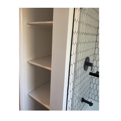 A bathroom with a shower and a closet with shelves