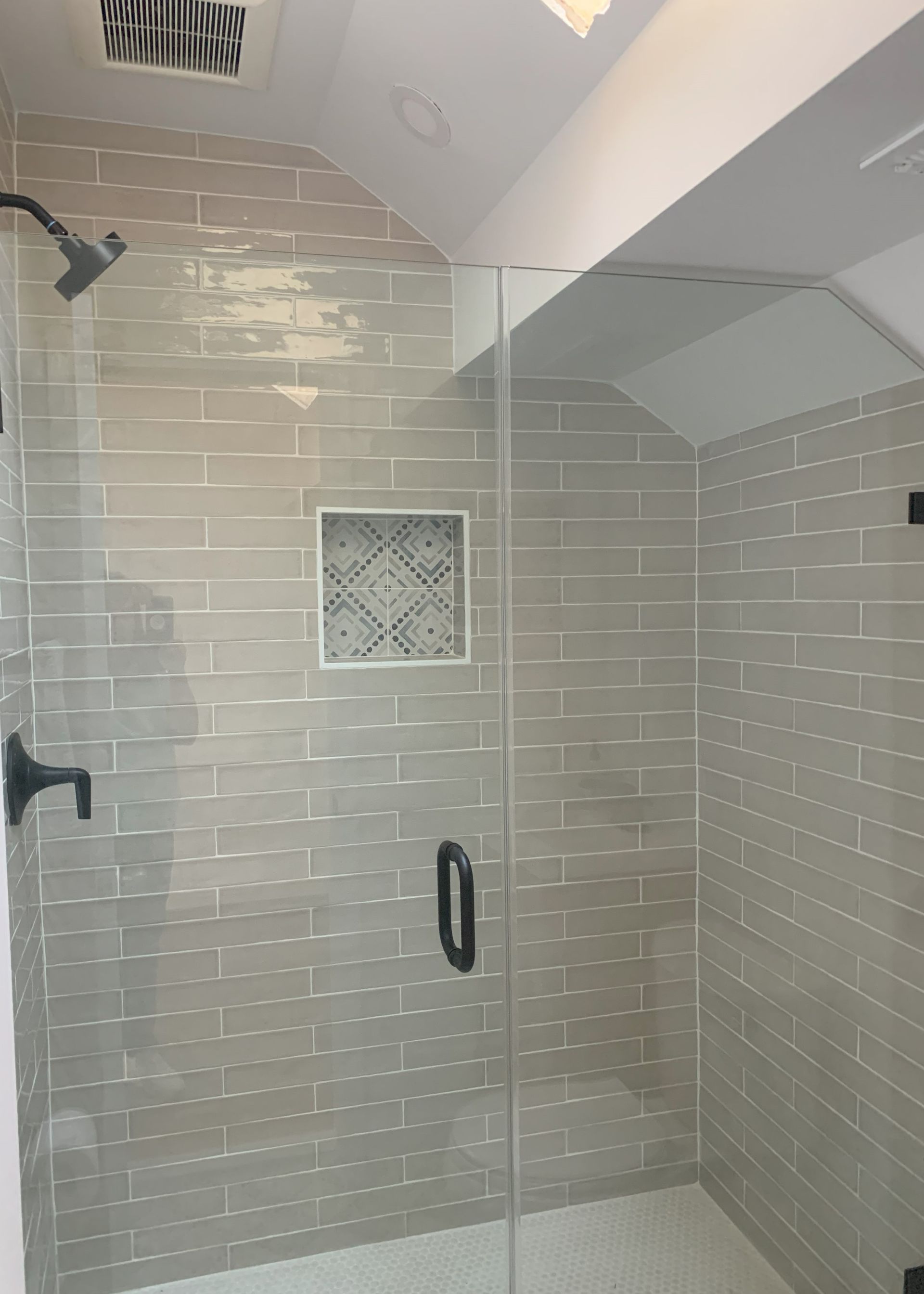 A bathroom with a walk in shower with a glass door.