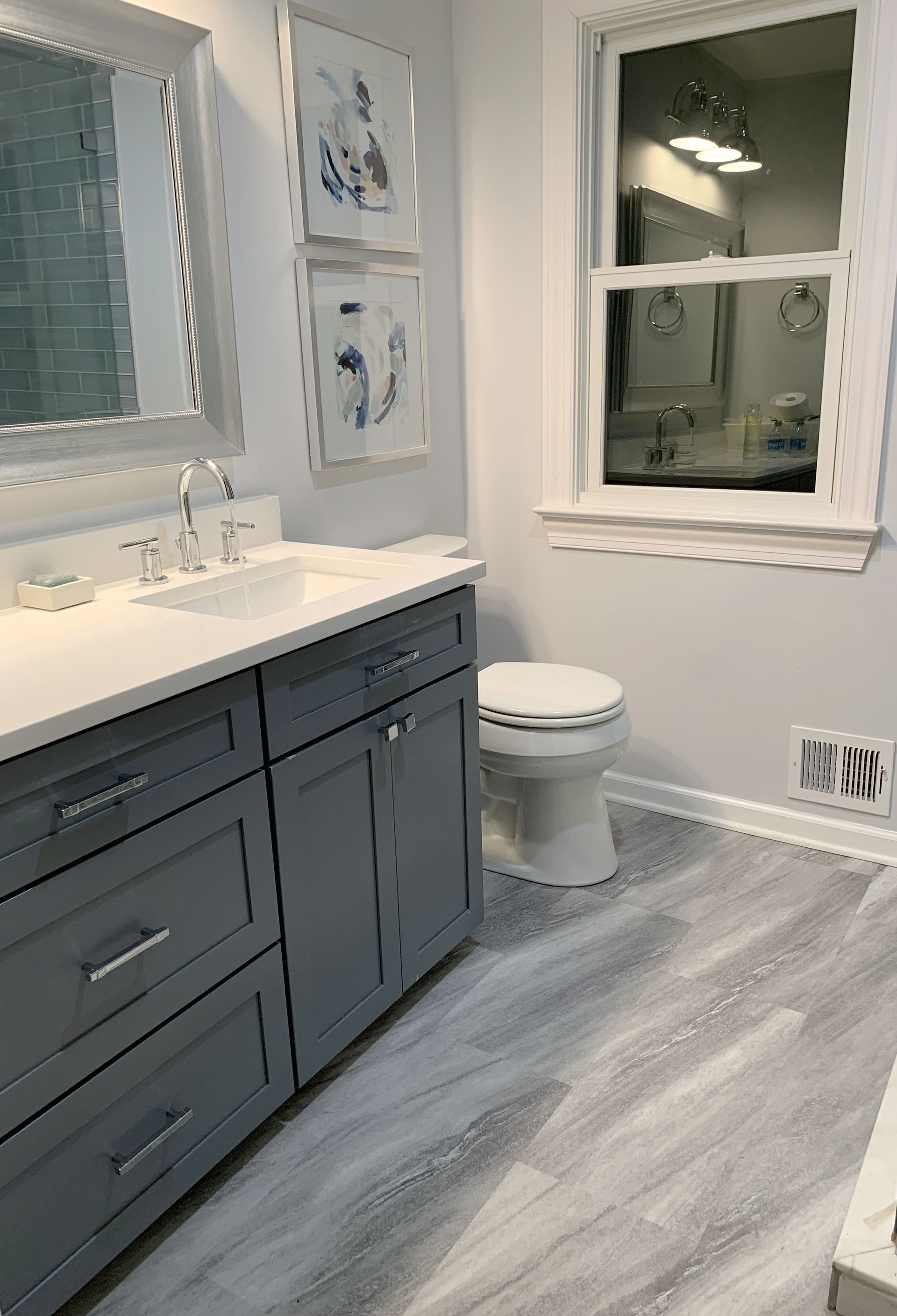 A bathroom with a sink , toilet , mirror and window.