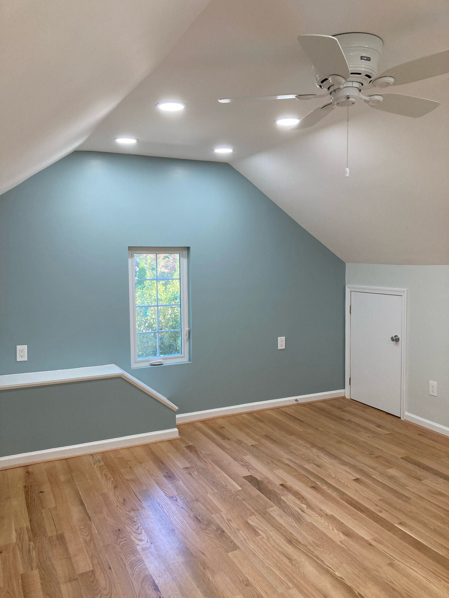 An empty room with a ceiling fan and a window.
