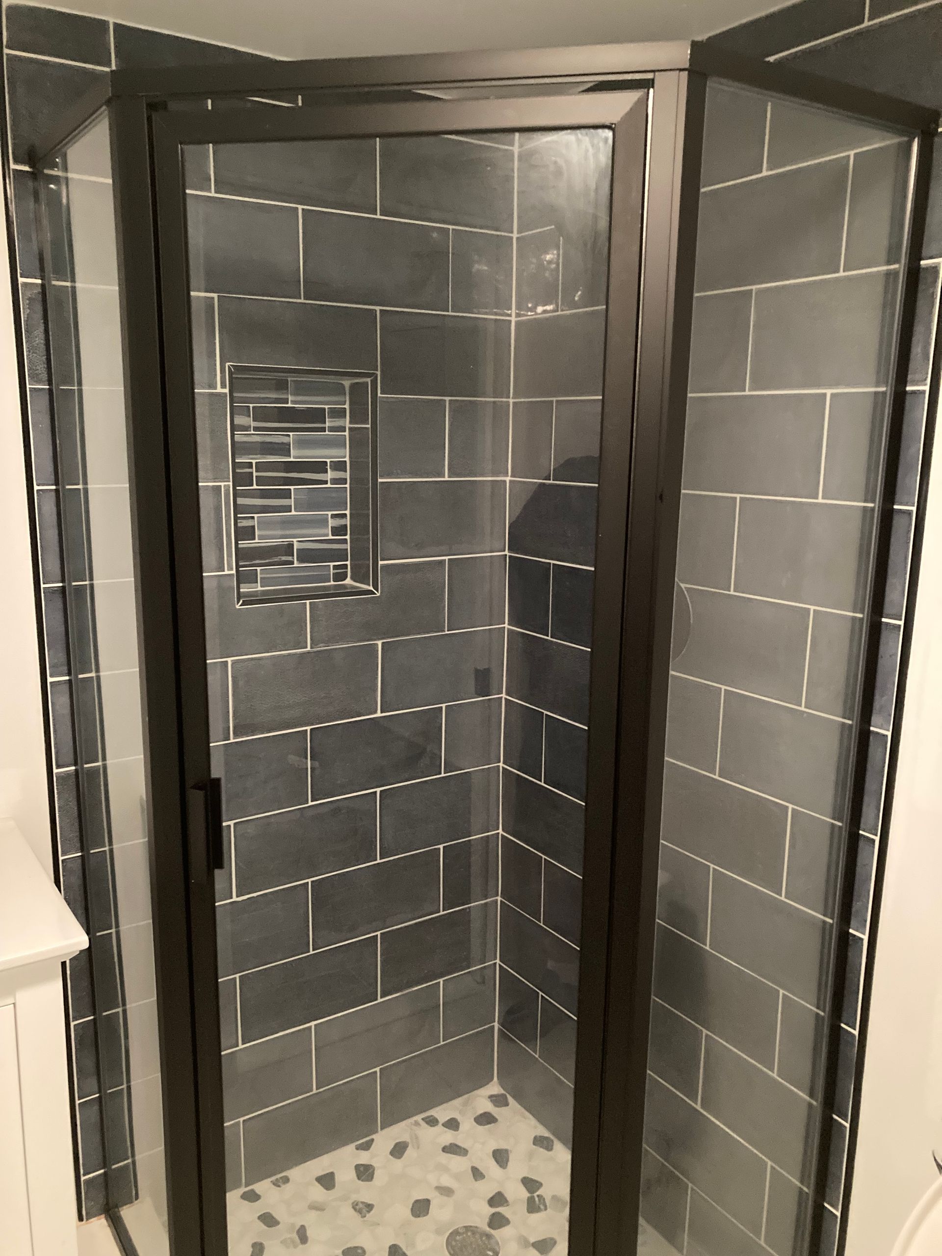 A bathroom with a walk in shower with a glass door.