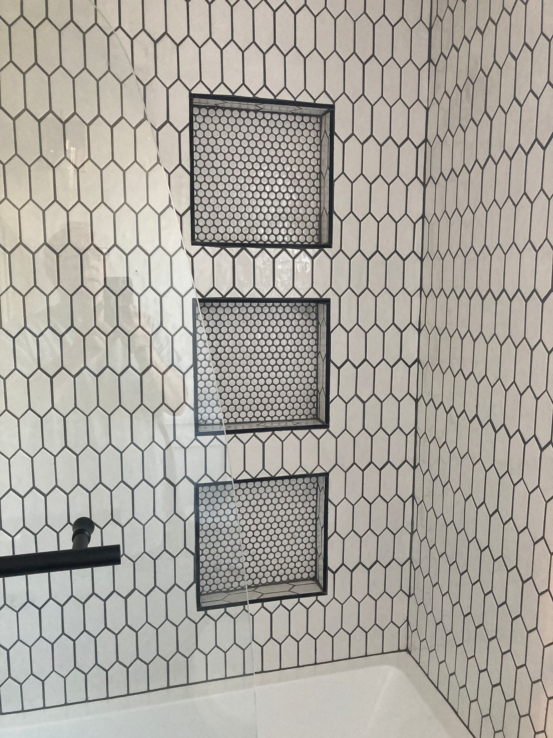 A bathroom with black and white tiles and a tub.