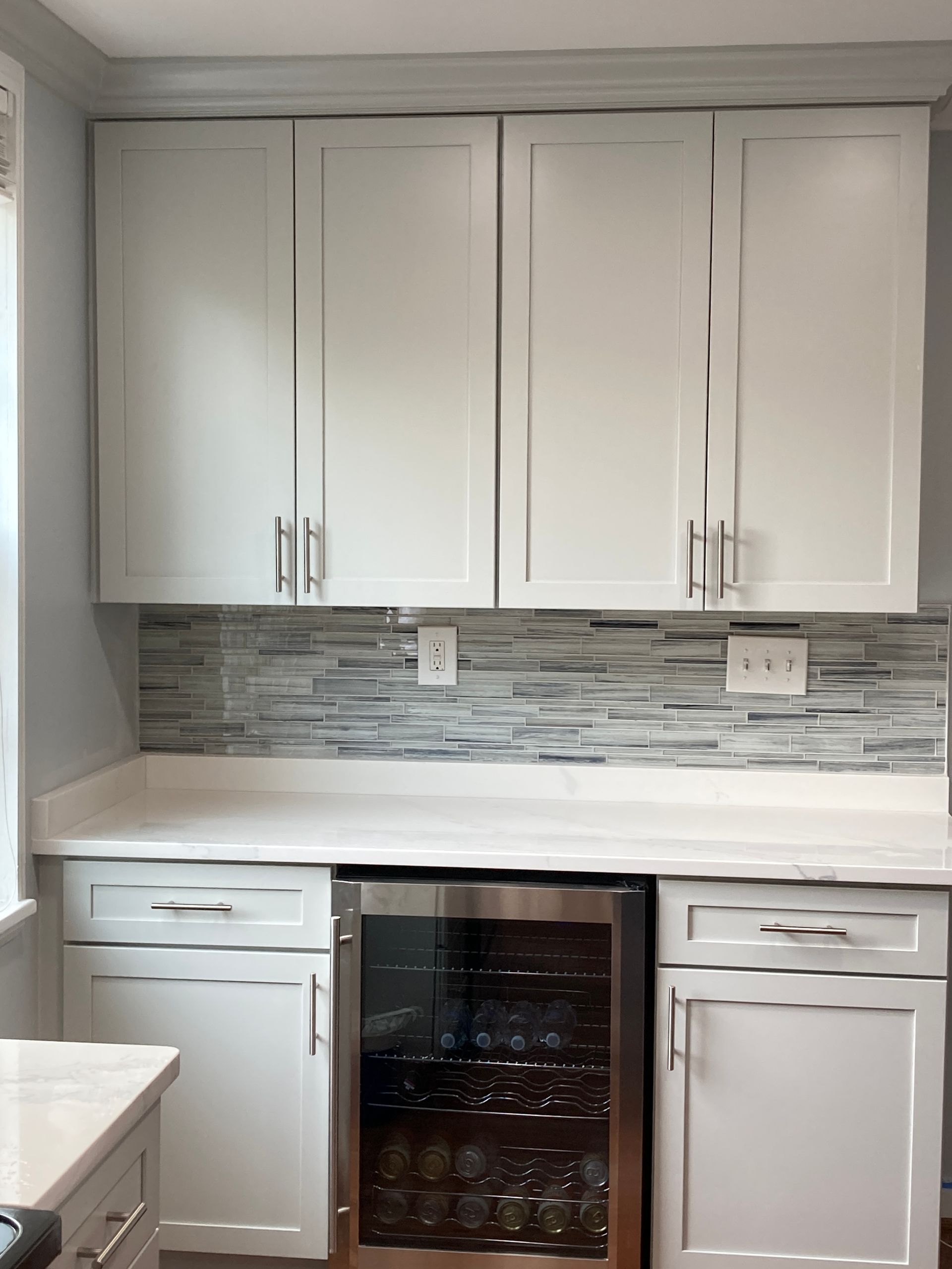 A kitchen with white cabinets and a wine cooler
