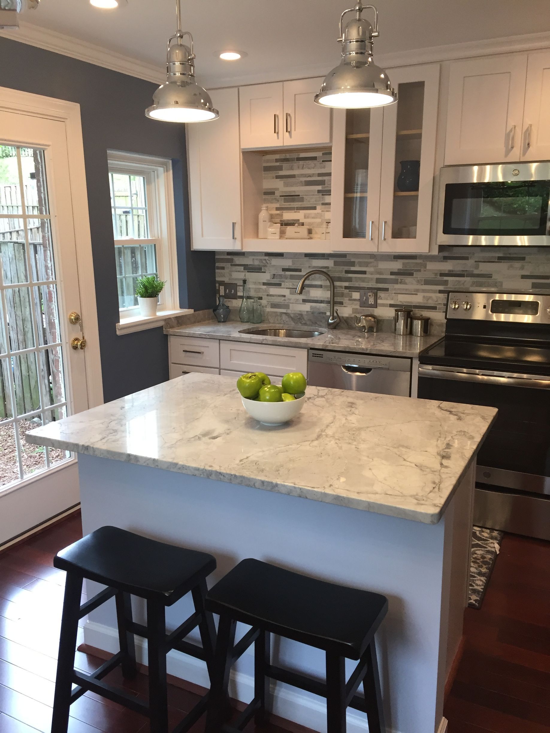 A kitchen with a large island and a bowl of apples on it