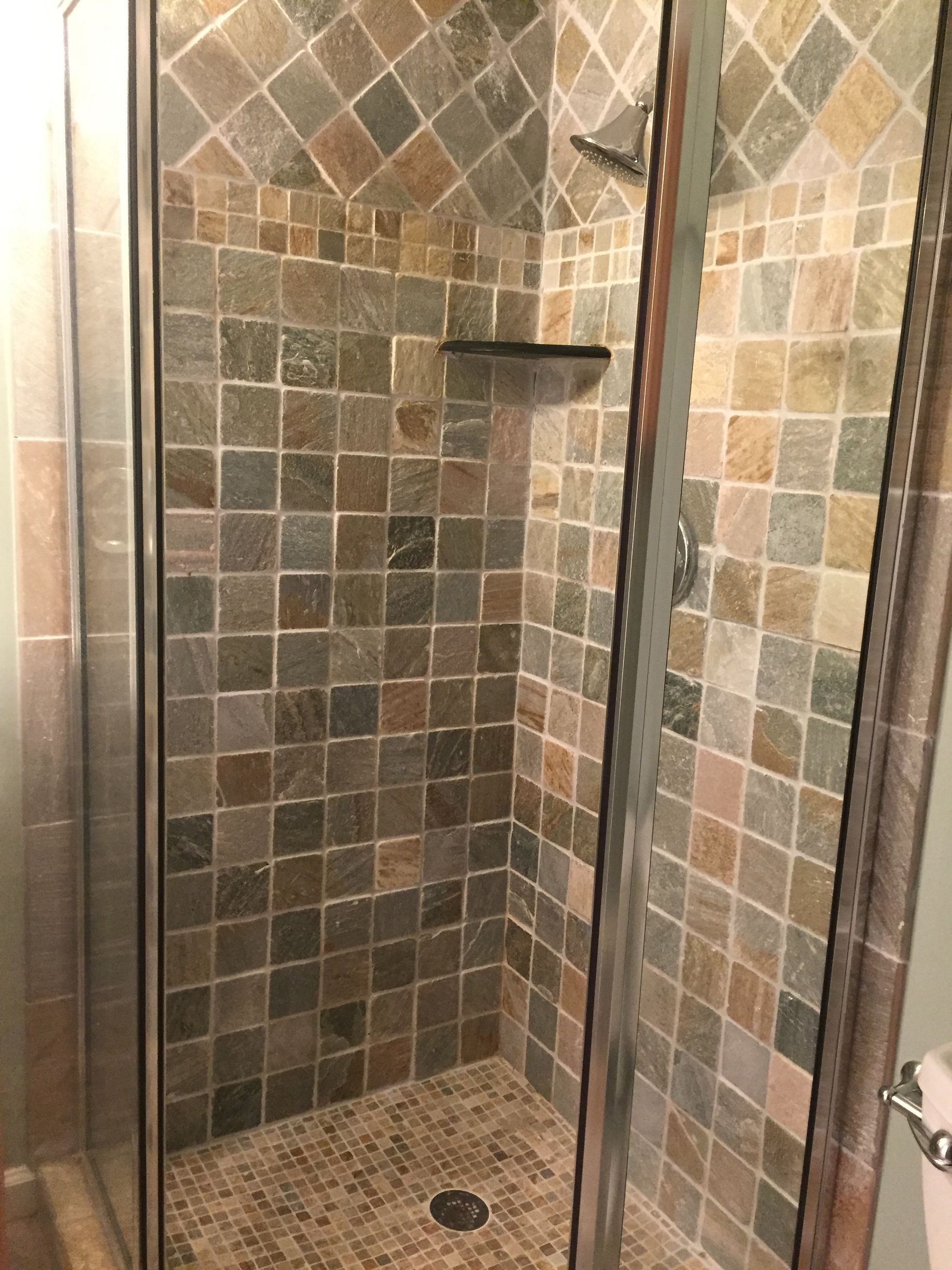 A shower stall with a glass door and tiled walls.