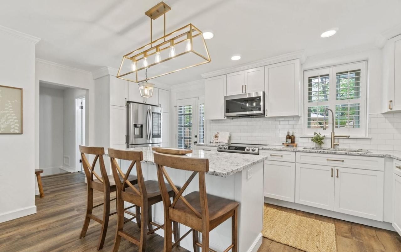 A kitchen with white cabinets , granite counter tops , stainless steel appliances and a large island.