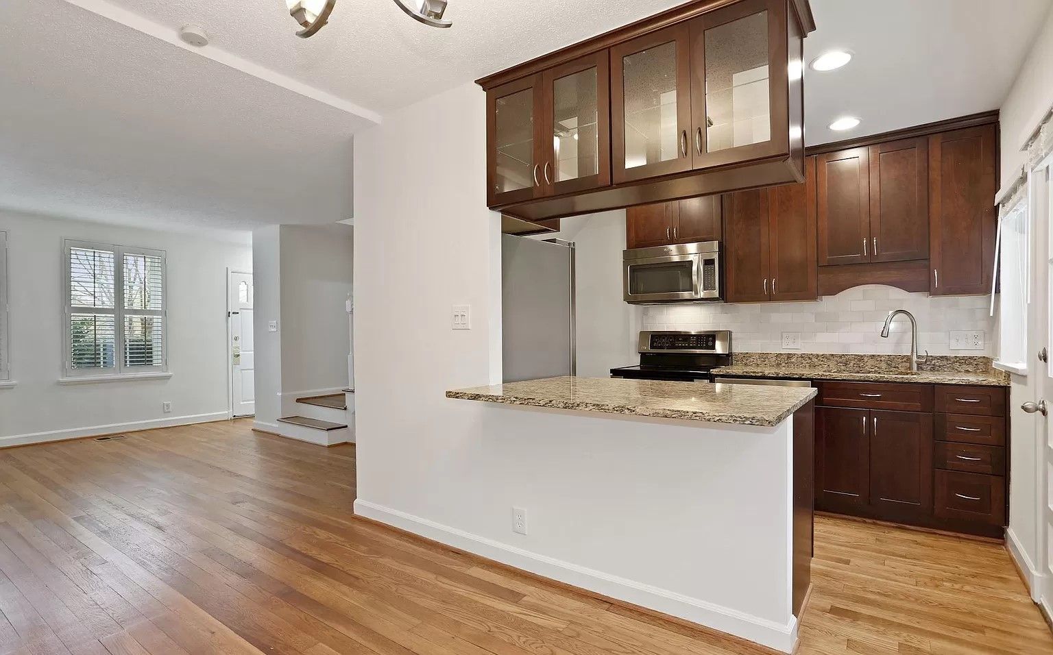 A kitchen with wooden cabinets , granite counter tops , a stove and a microwave.