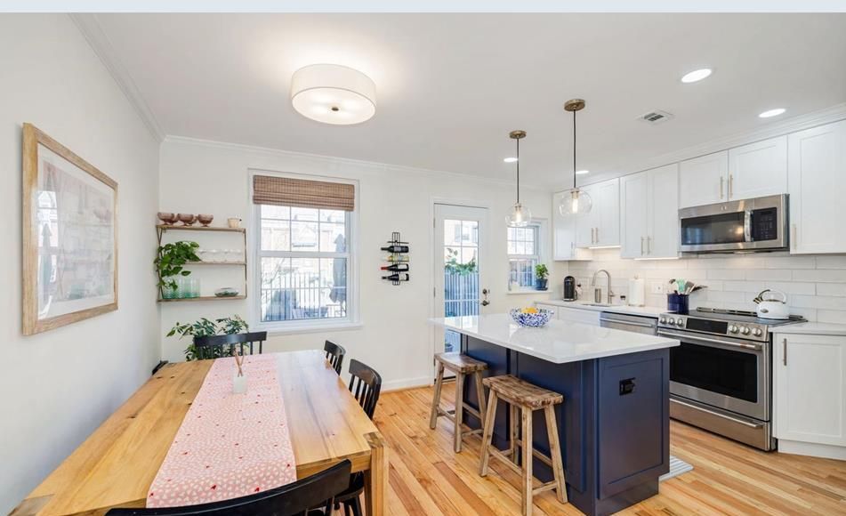 A kitchen with a wooden table and chairs and a blue island.