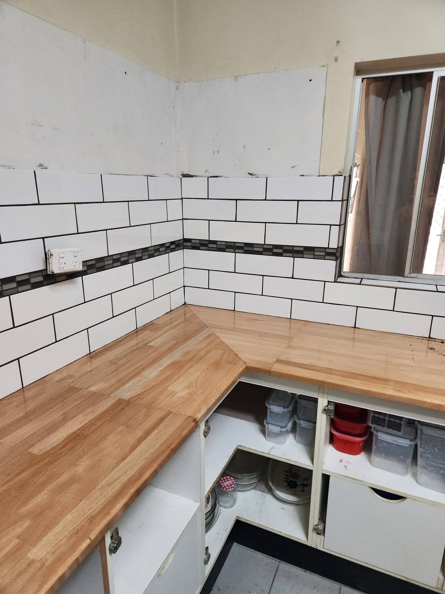 Partially Tiled Kitchen Corner with Wooden Countertop, White Cabinets — Sun Co Concrete And Construction in Dimbulah, QLD