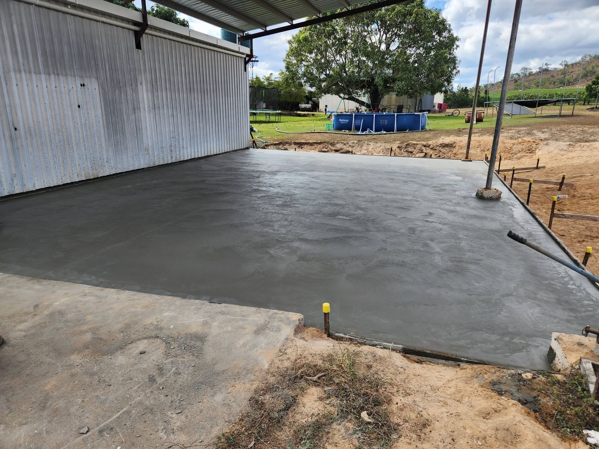 Freshly Poured Concrete Patio Beside a White Building in A Rural Yard — Sun Co Concrete And Construction in Dimbulah, QLD