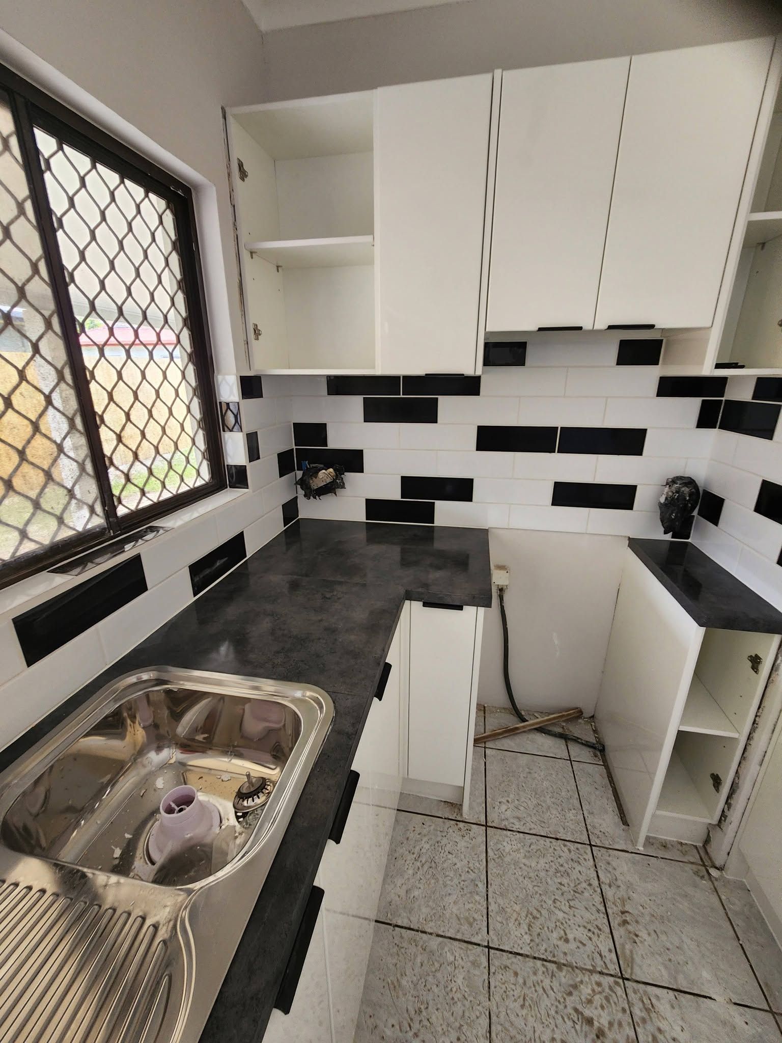 Small Kitchen Renovation with Black Countertops, White Cabinets — Sun Co Concrete And Construction in Dimbulah, QLD