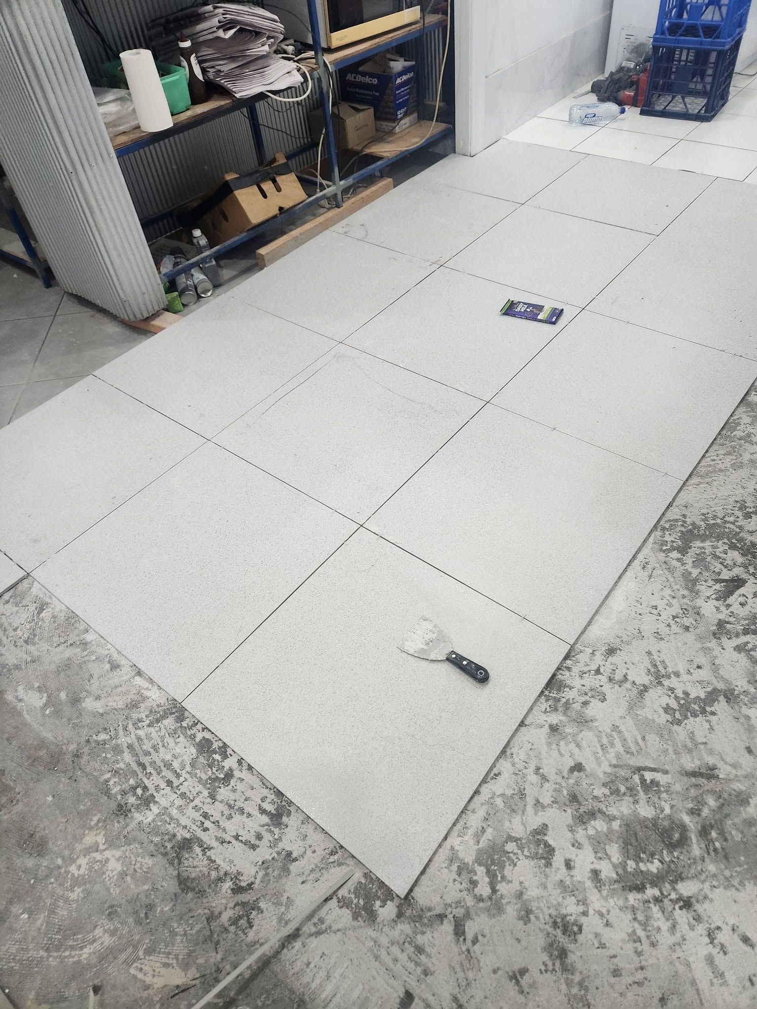 Floor Tiles Laid out On a Workshop Floor Beside Shelves and Tools — Sun Co Concrete And Construction in Dimbulah, QLD
