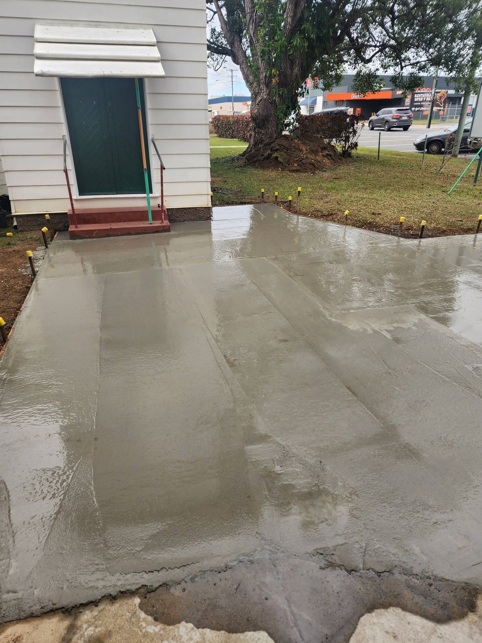 Wet Concrete Walkway Beside a White Building Entrance — Sun Co Concrete And Construction in Dimbulah, QLD