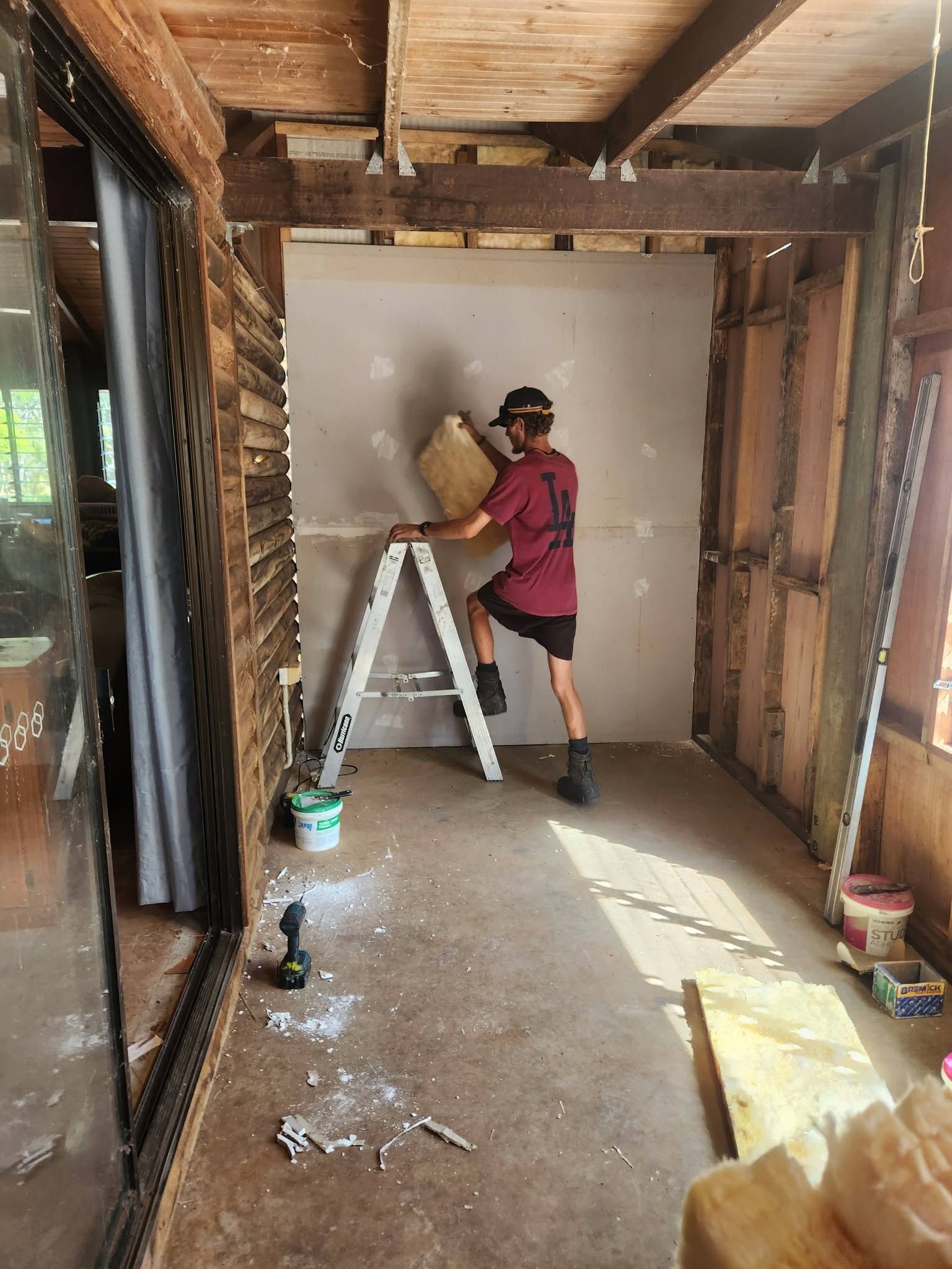 Person Painting a Wall Inside a Partially Renovated Room — Sun Co Concrete And Construction in Dimbulah, QLD