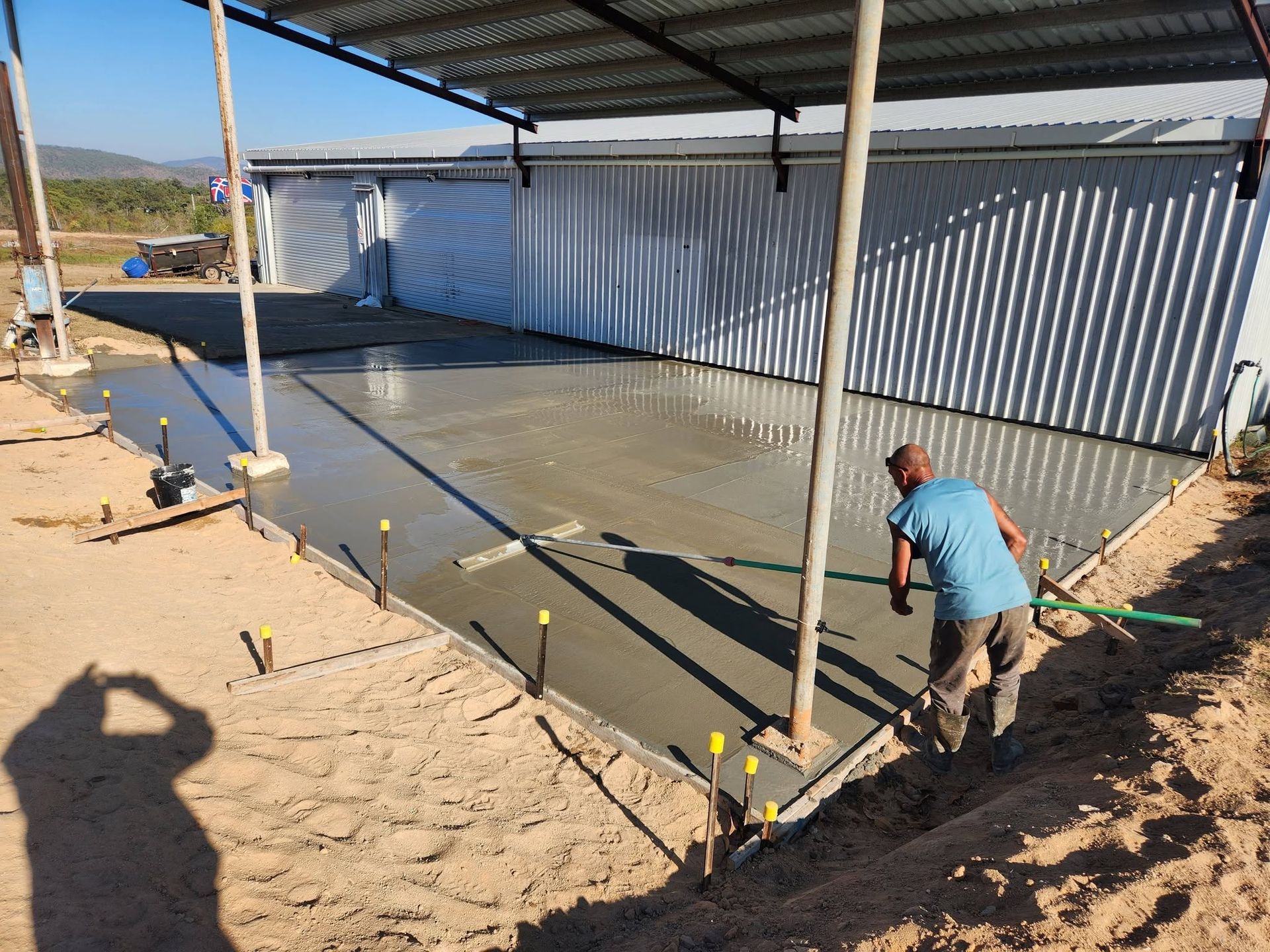 Worker Smoothing Wet Concrete in A Covered Construction Area — Sun Co Concrete And Construction in Dimbulah, QLD
