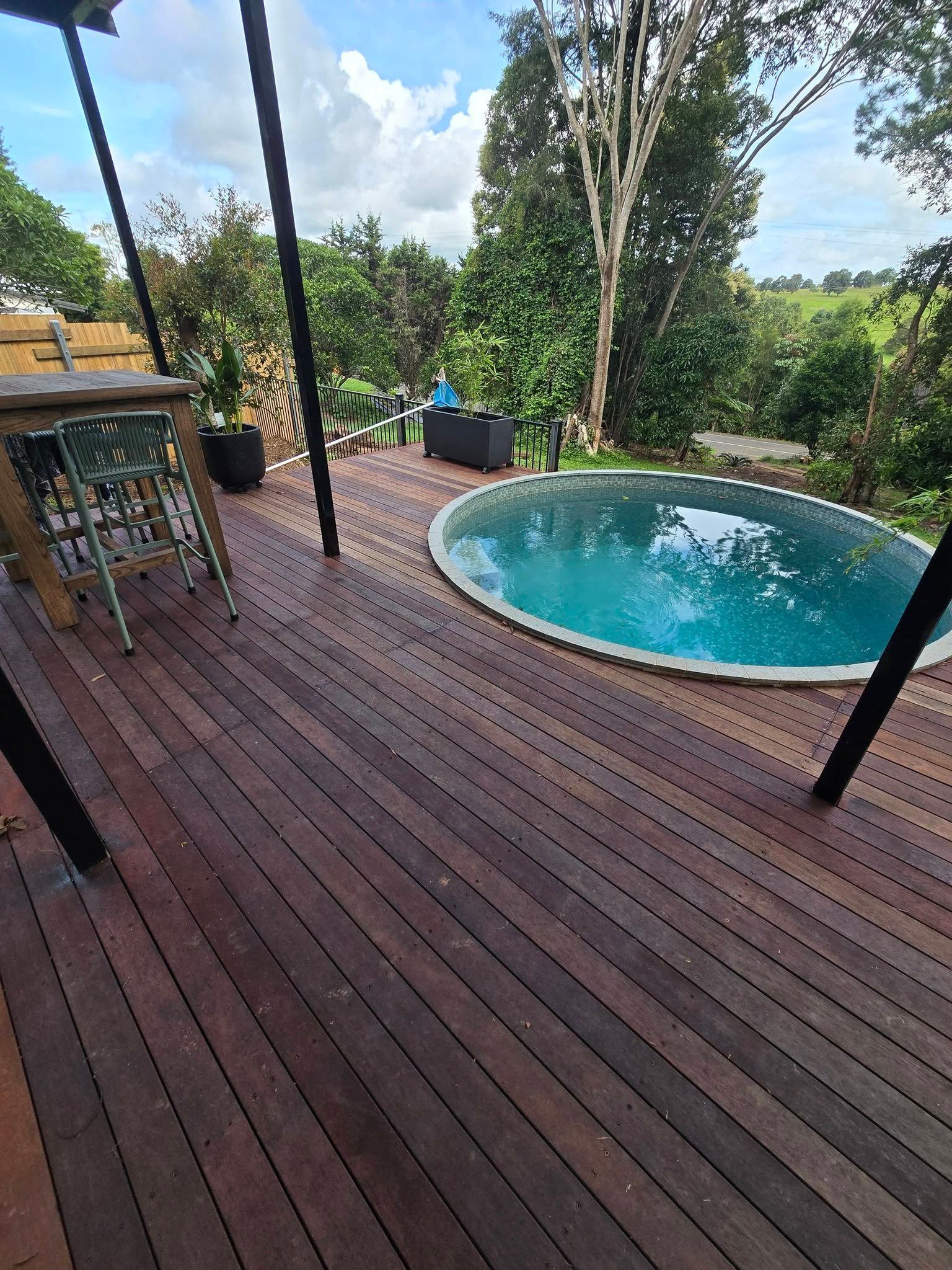 Wooden Deck Overlooking a Turquoise Round Pool — Sun Co Concrete And Construction in Dimbulah, QLD