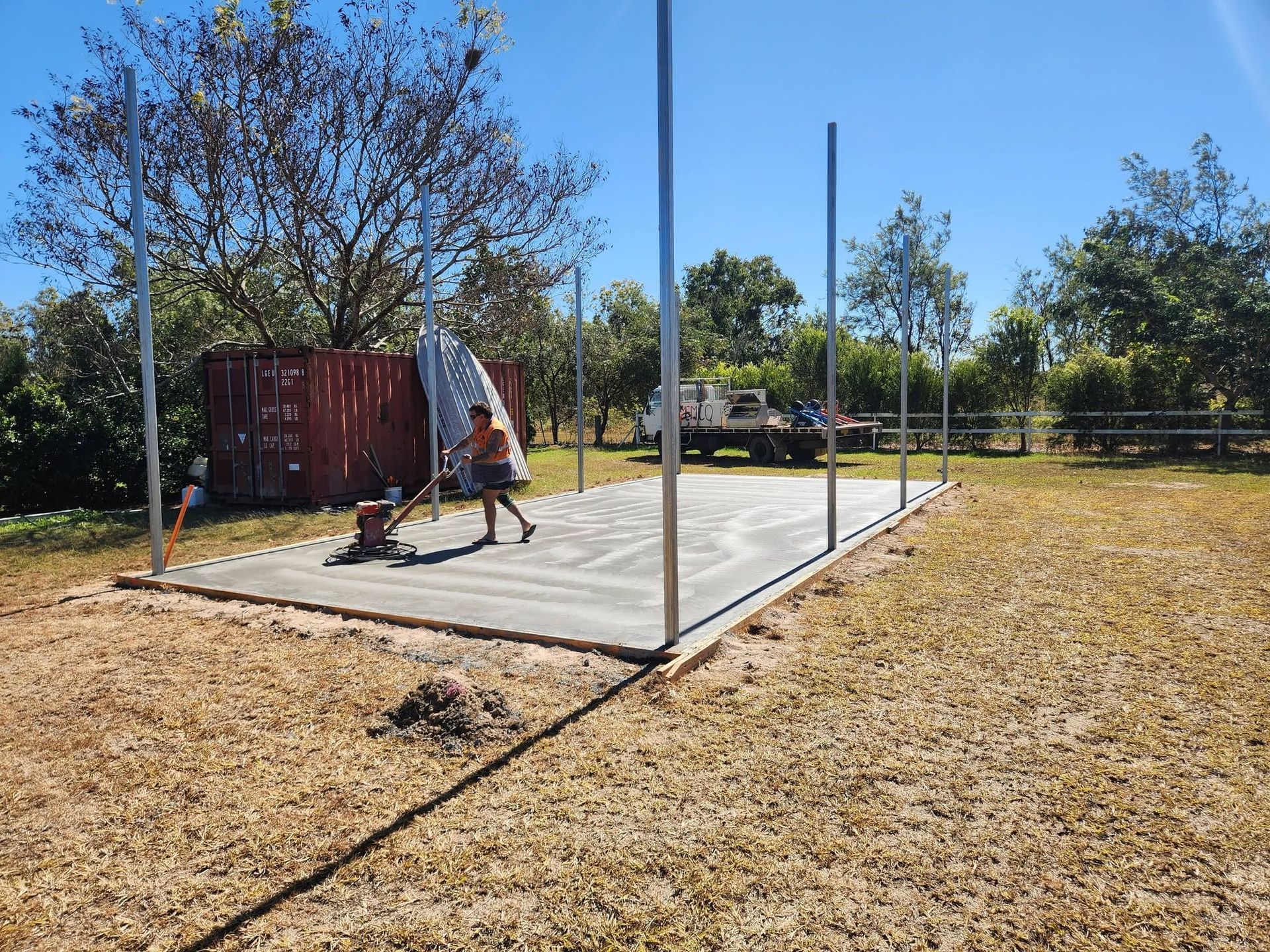 Person Leveling Concrete Slab on A Sunny Construction Site — Sun Co Concrete And Construction in Dimbulah, QLD