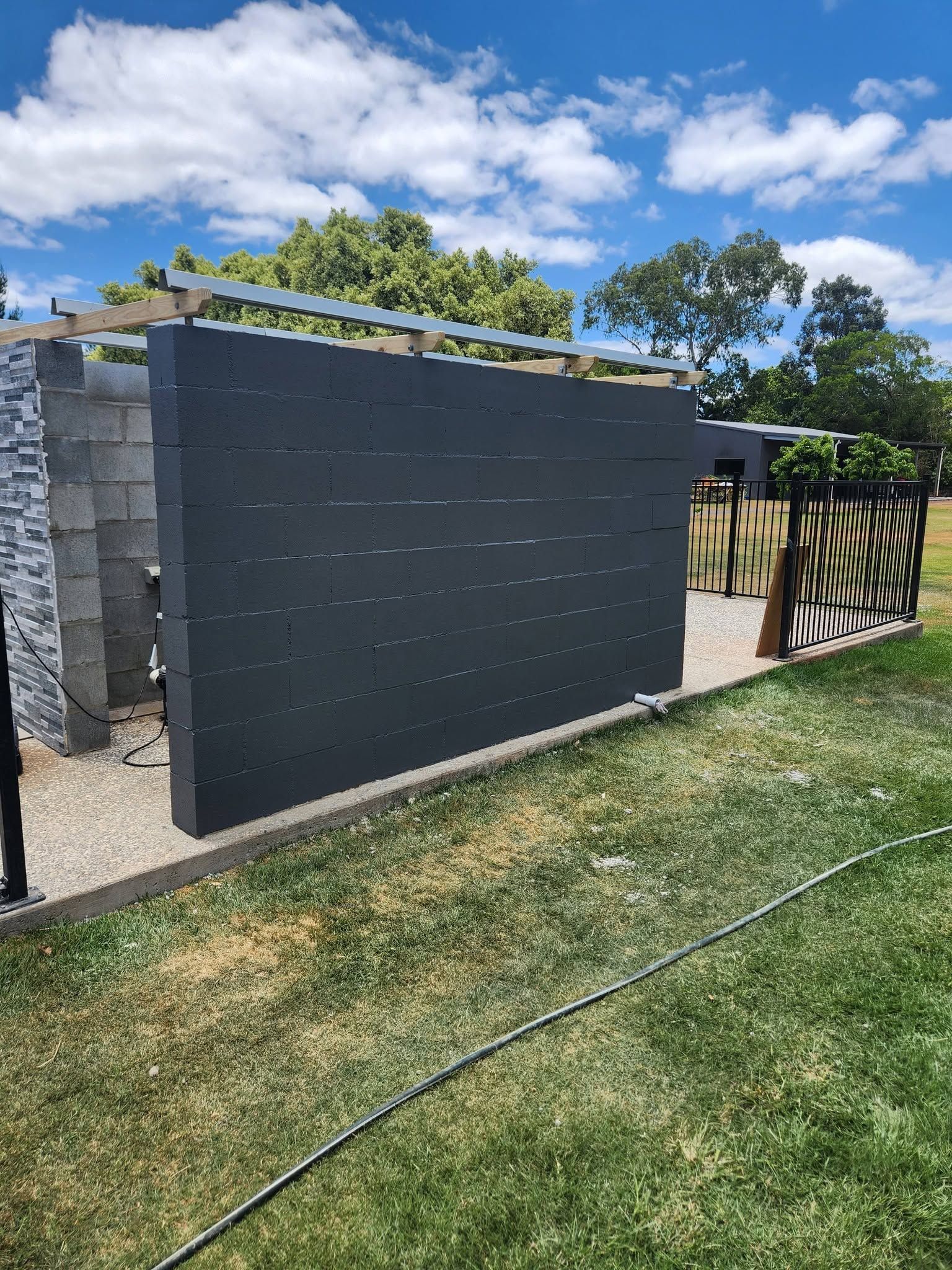 Black Privacy Fence Beside Stone Pillars — Sun Co Concrete And Construction in Mareeba, QLD