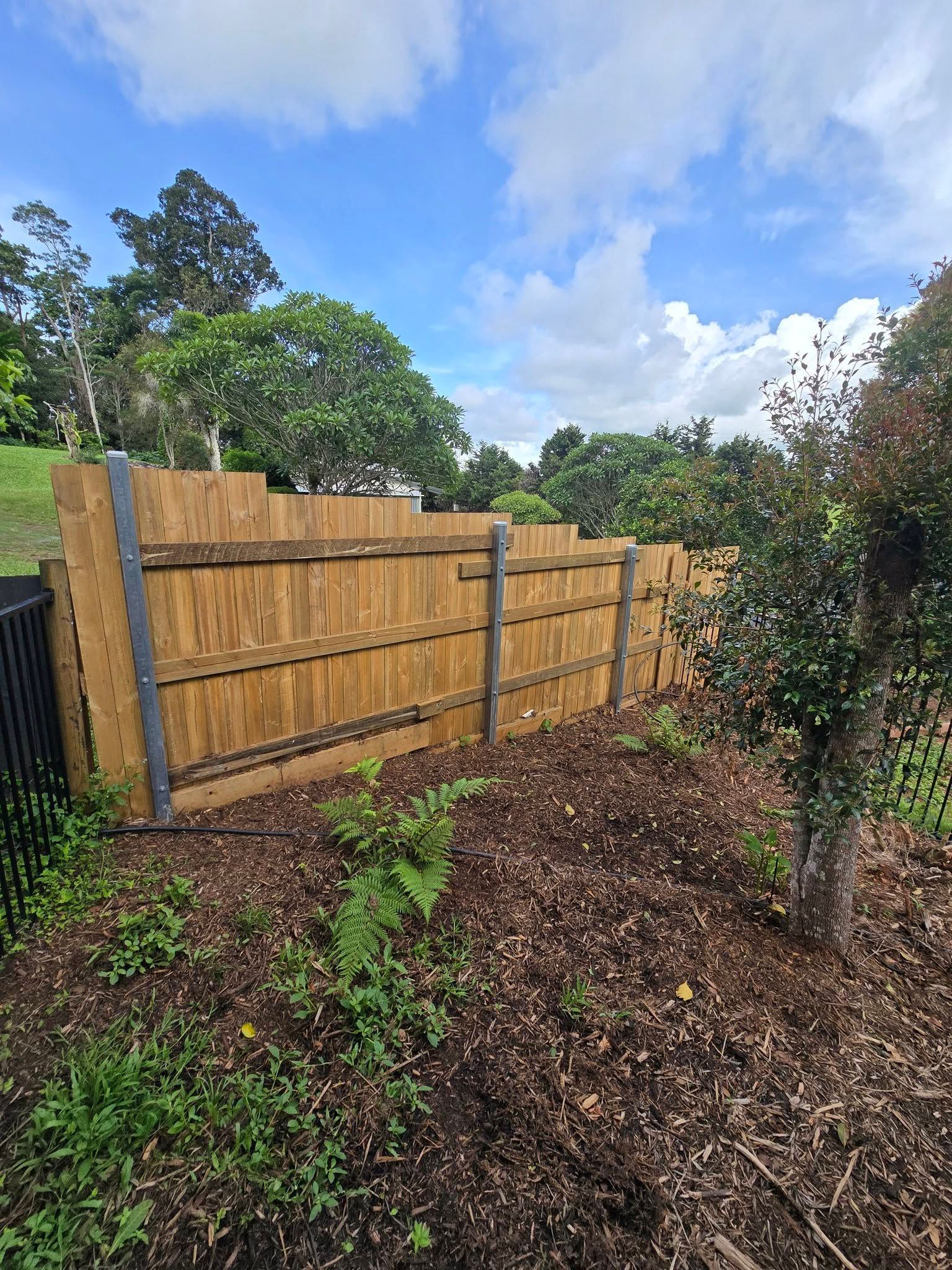 Wooden Fence Enclosing a Garden Bed with Trees — Sun Co Concrete And Construction in Dimbulah, QLD