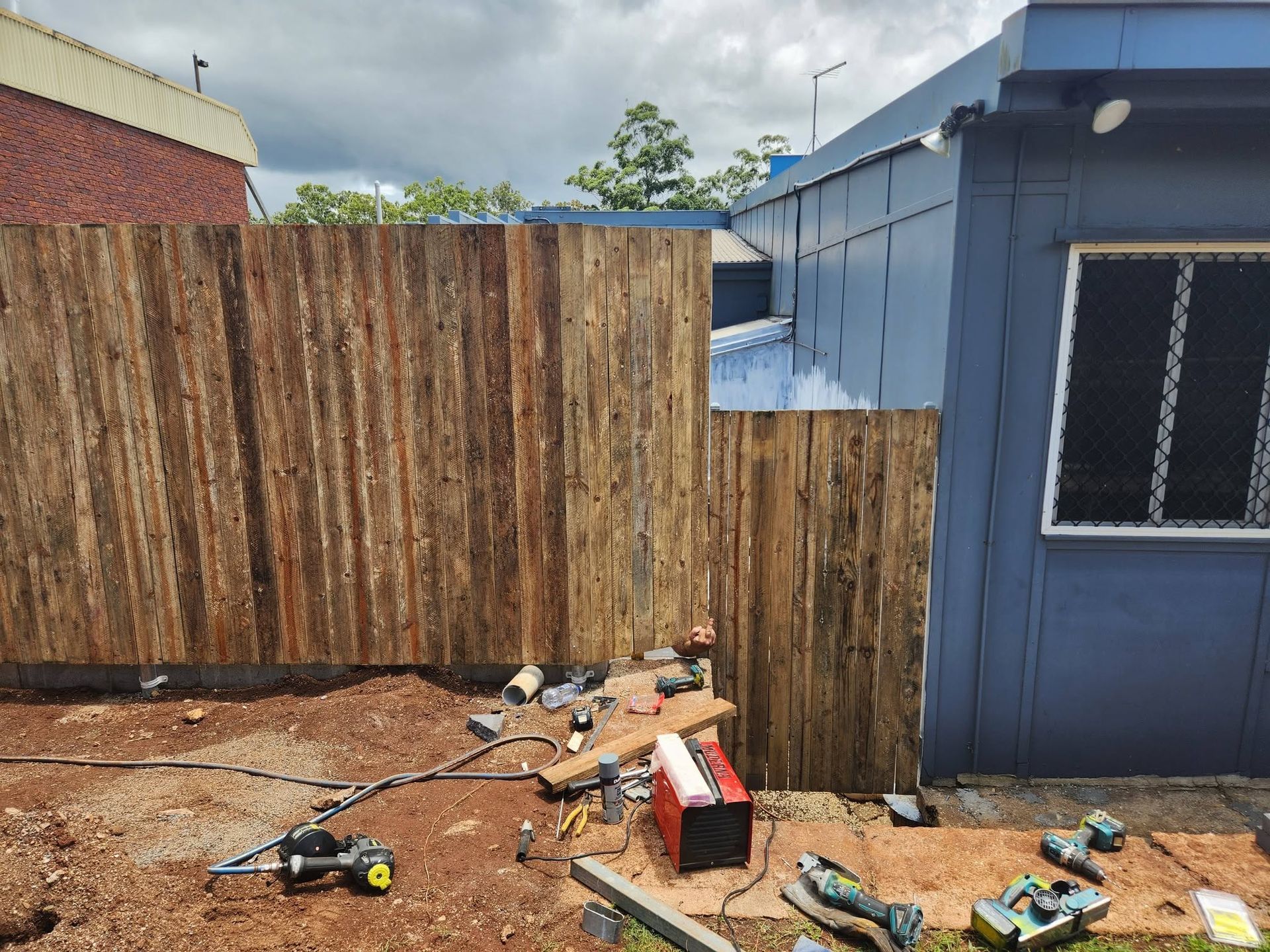Backyard with Tall Wooden Fence, Blue Building — Sun Co Concrete And Construction in Dimbulah, QLD