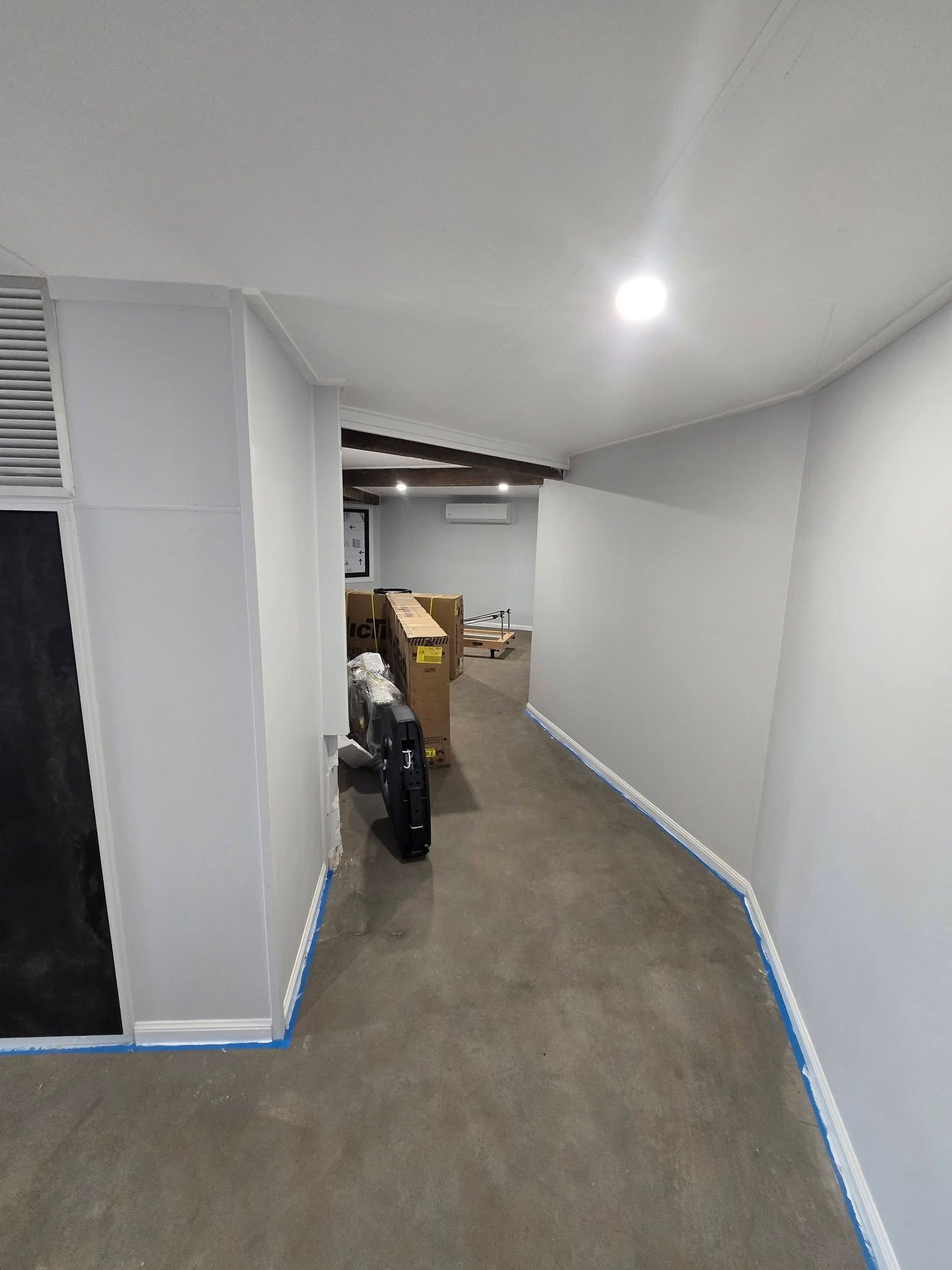 Narrow Gray Hallway with Blue Tape on The Floor — Sun Co Concrete And Construction in Dimbulah, QLD