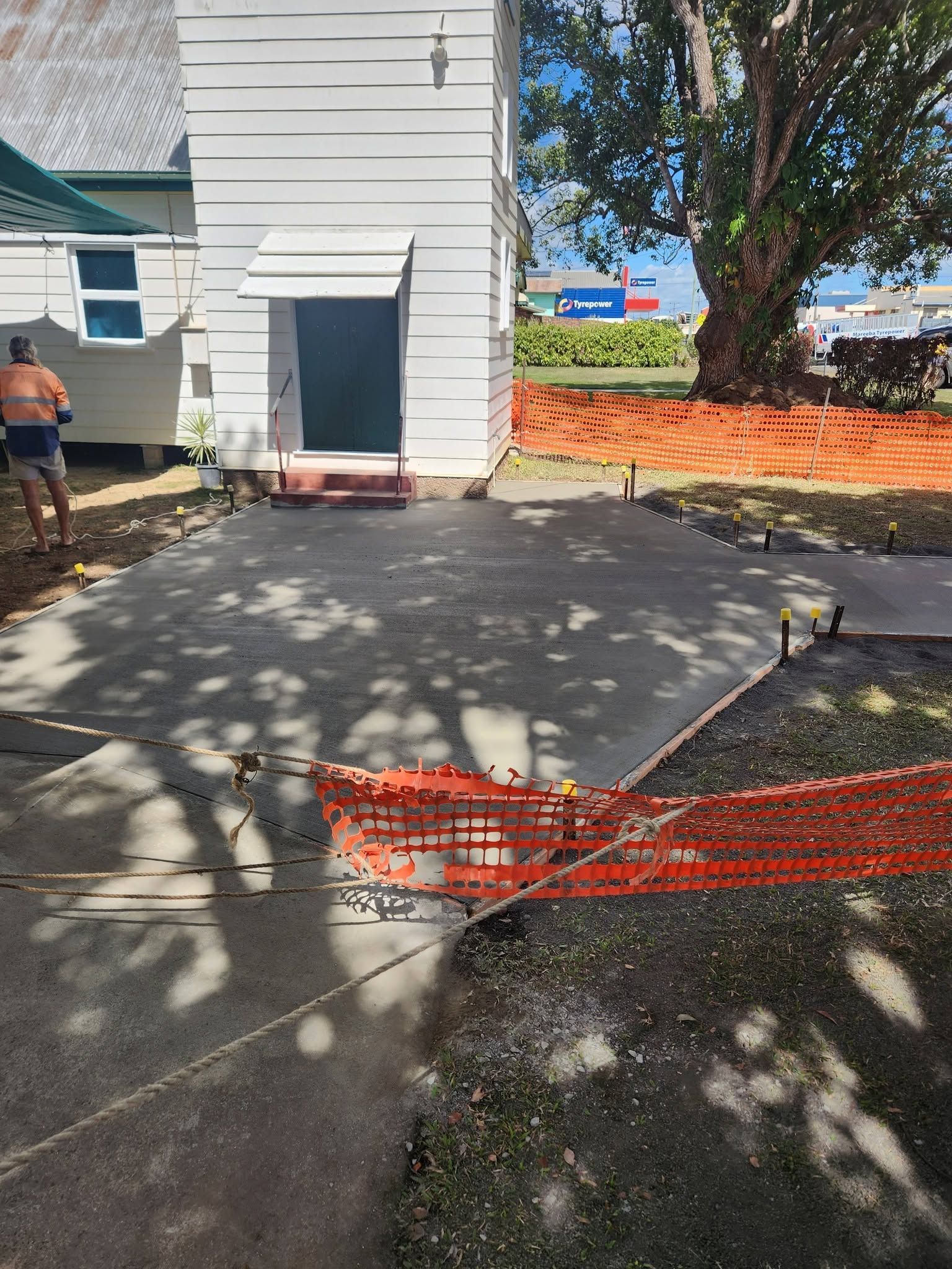 Backyard Concrete Patio Beside White House, with Orange Safety Fencing — Sun Co Concrete And Construction in Dimbulah, QLD