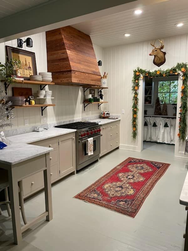 A white kitchen drawer pulled open next to a built-in oven, with clean, minimalist white cabinets and a dark countertop.