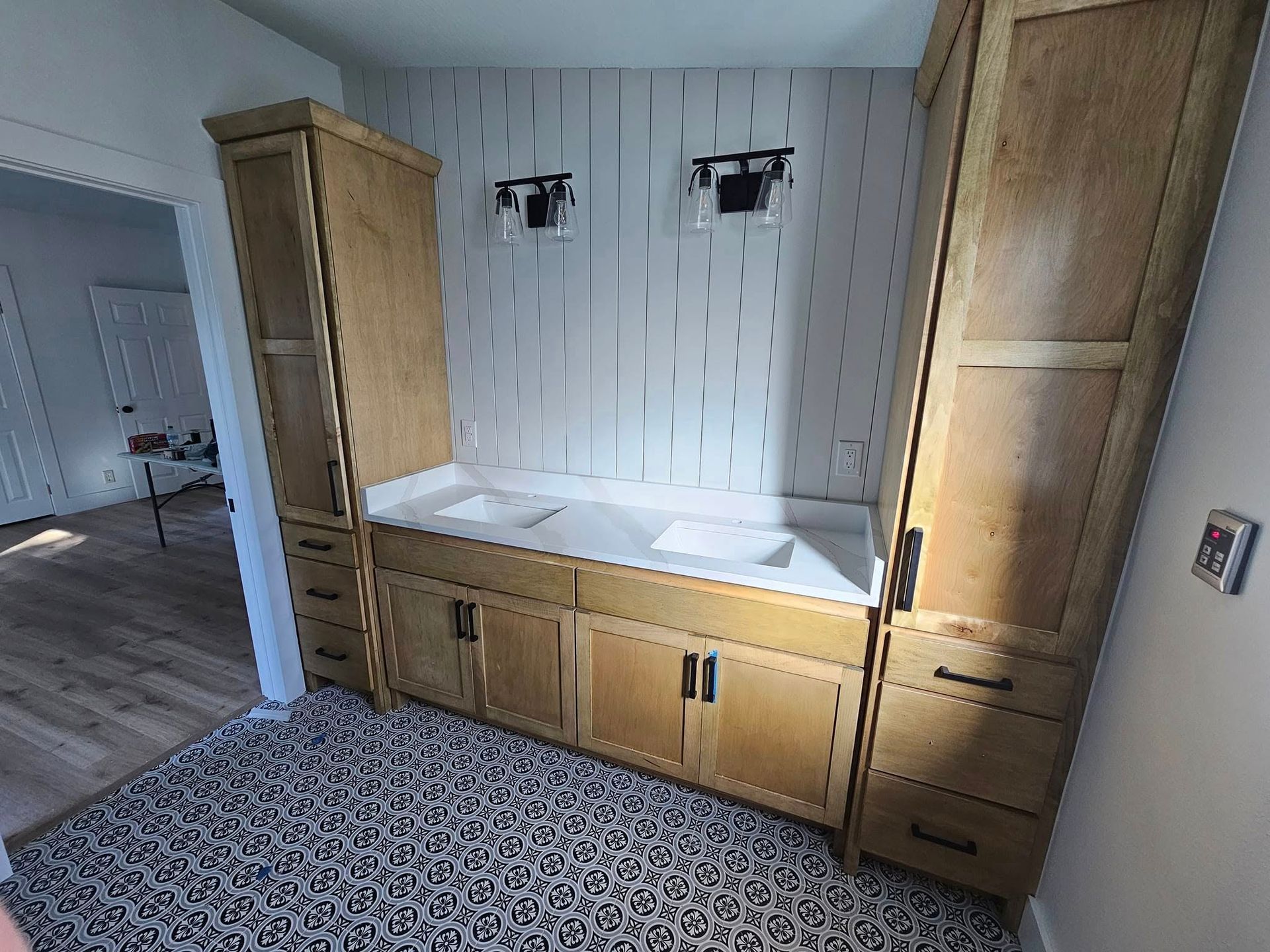 A modern bathroom with white marble-patterned tiles, a floating vanity, a toilet, and a glass-enclosed bathtub shower.