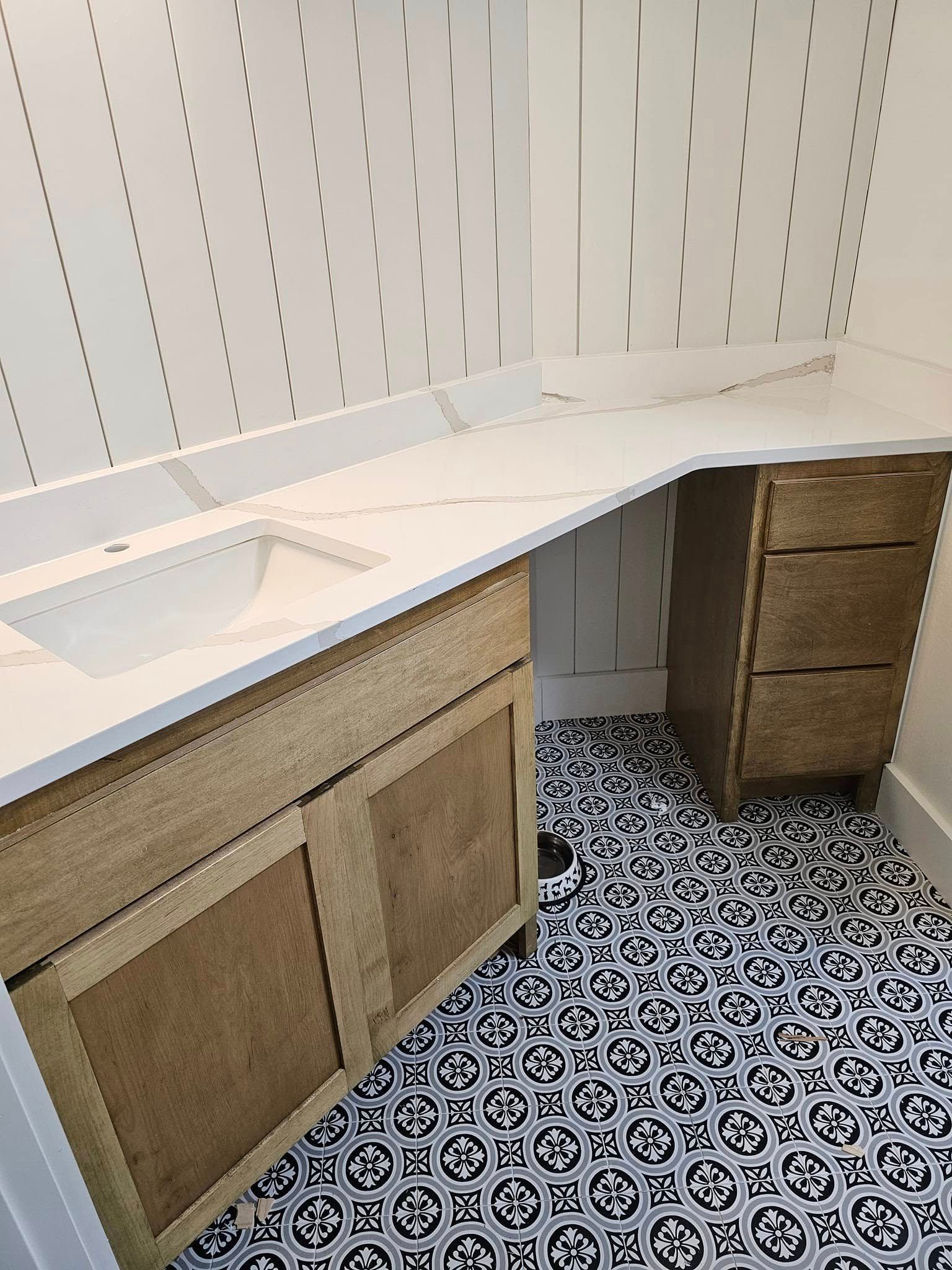 An organized bathroom storage cabinet with stacked white towels, wicker baskets, toilet paper rolls, and toiletry bottles.