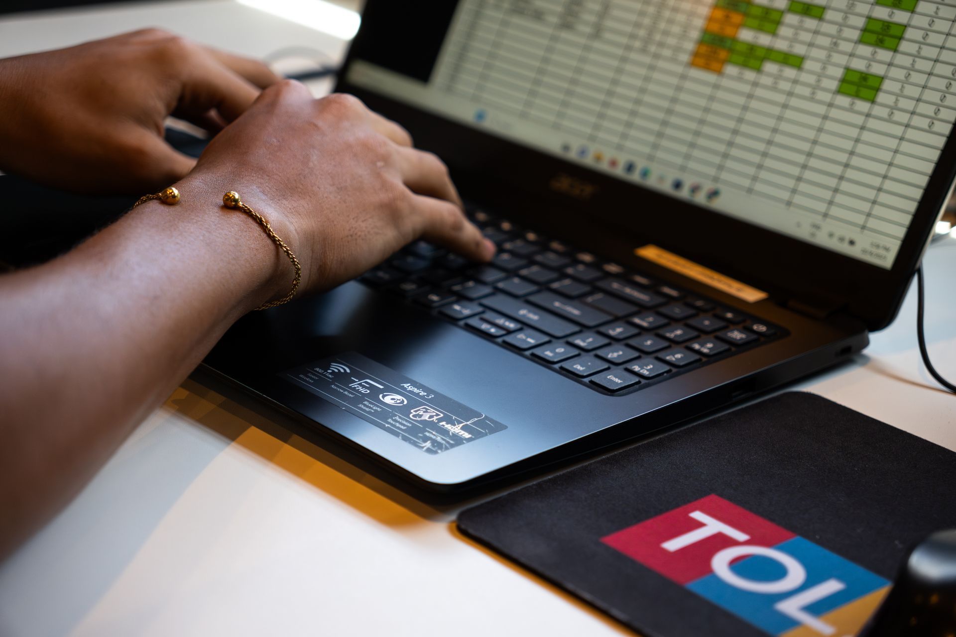 Een persoon typt op een laptop naast een muismat met de tekst toll