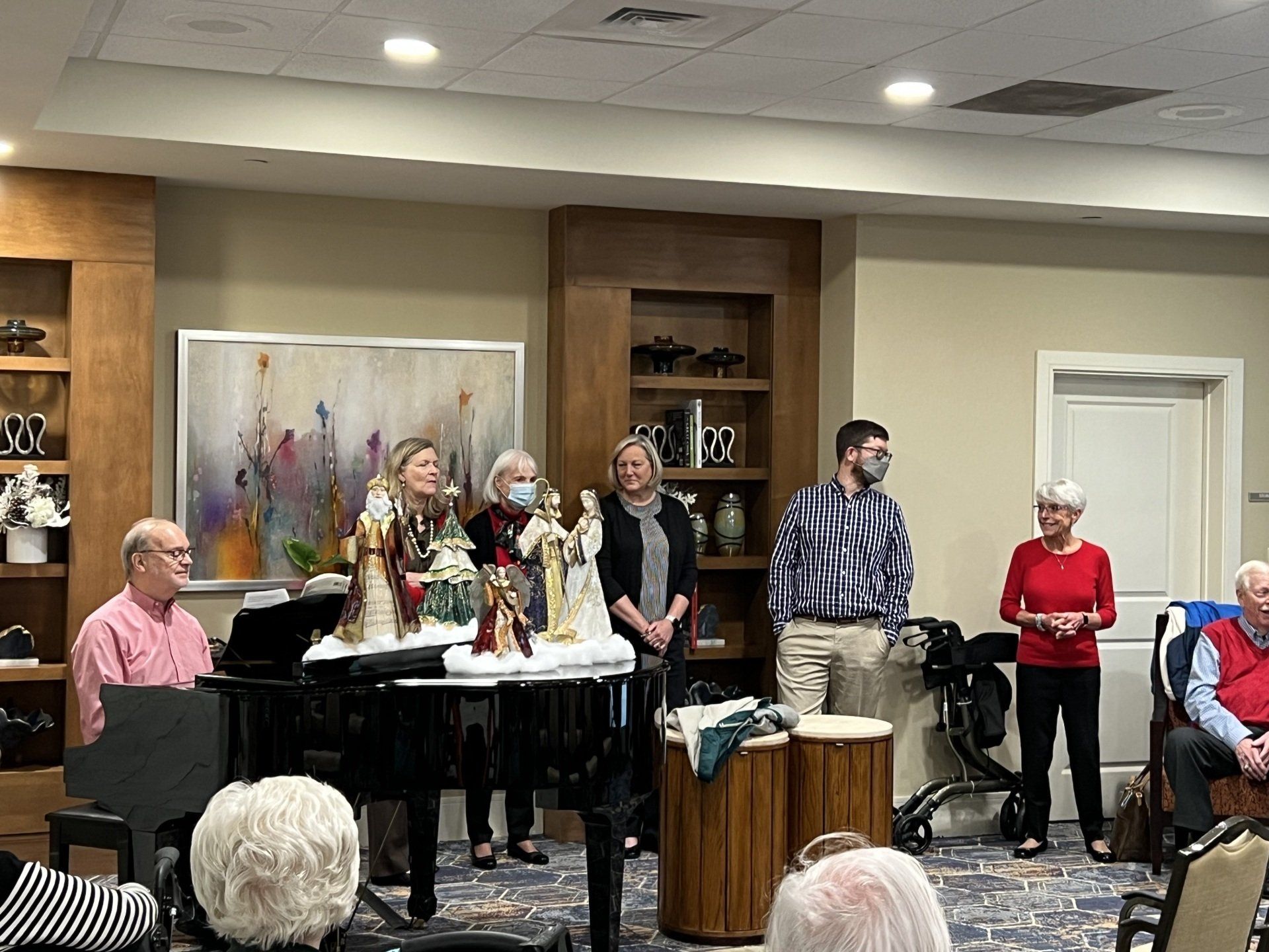 A musical performance in a room: a pianist, singers, and audience.