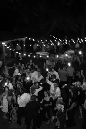 Crowded nighttime outdoor party with people dancing under string lights
